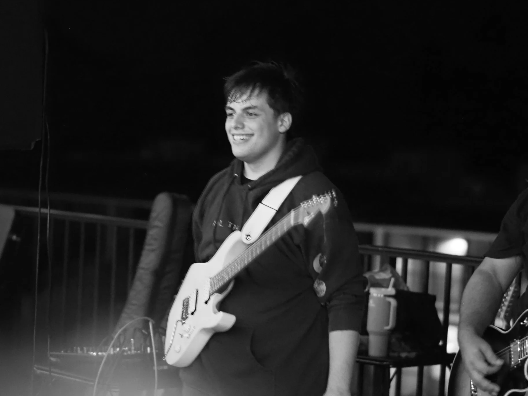 A young man smiling and holding an electric guitar.