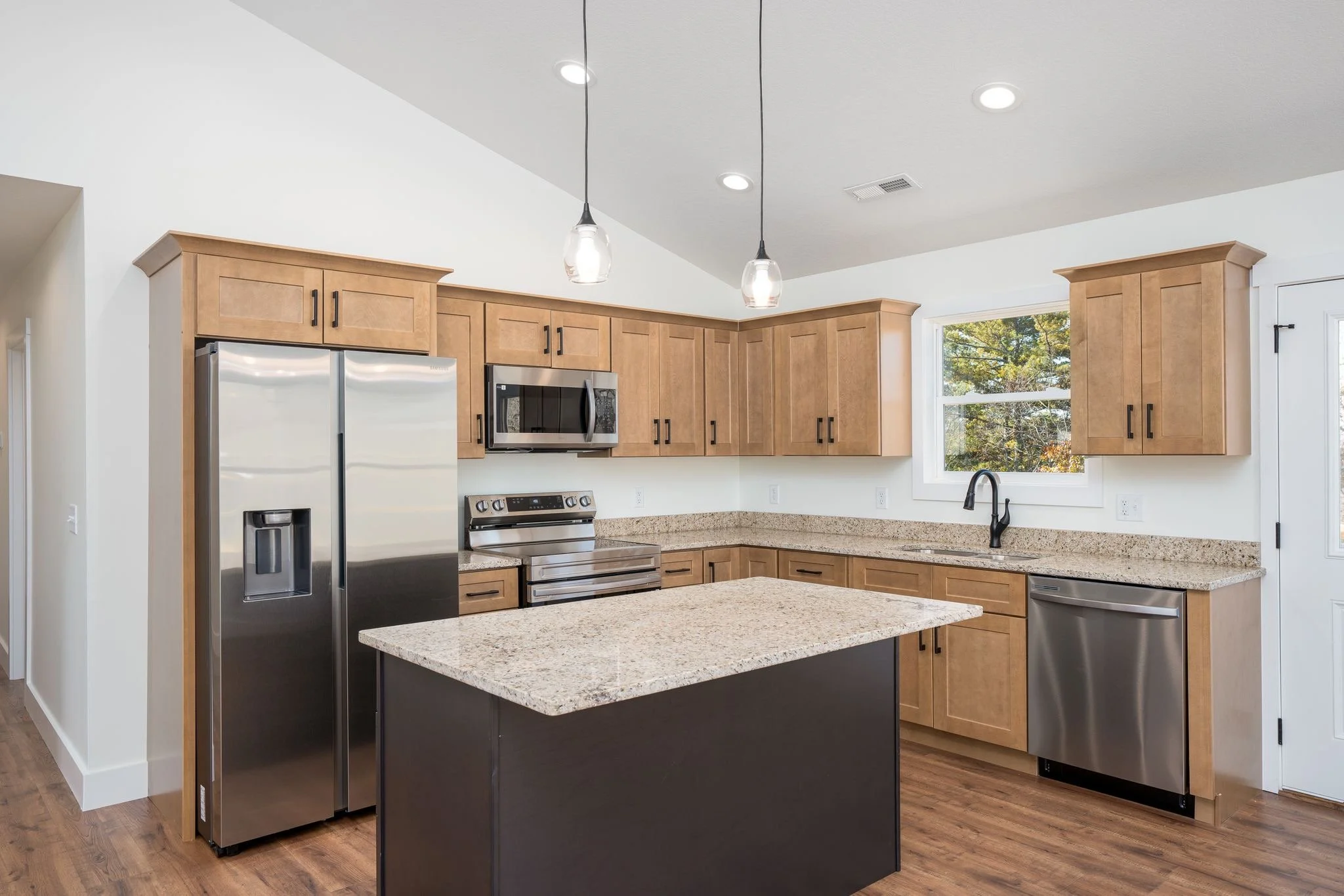 Modern kitchen with wood cabinets, granite countertops, stainless steel appliances, and a small kitchen island.