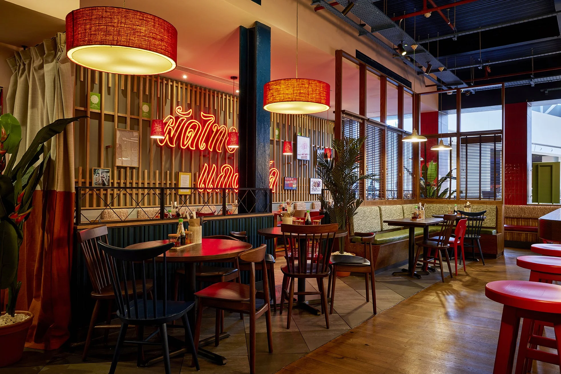 Interior of a cozy restaurant with wooden furniture, colorful lighting, and decorative plants.