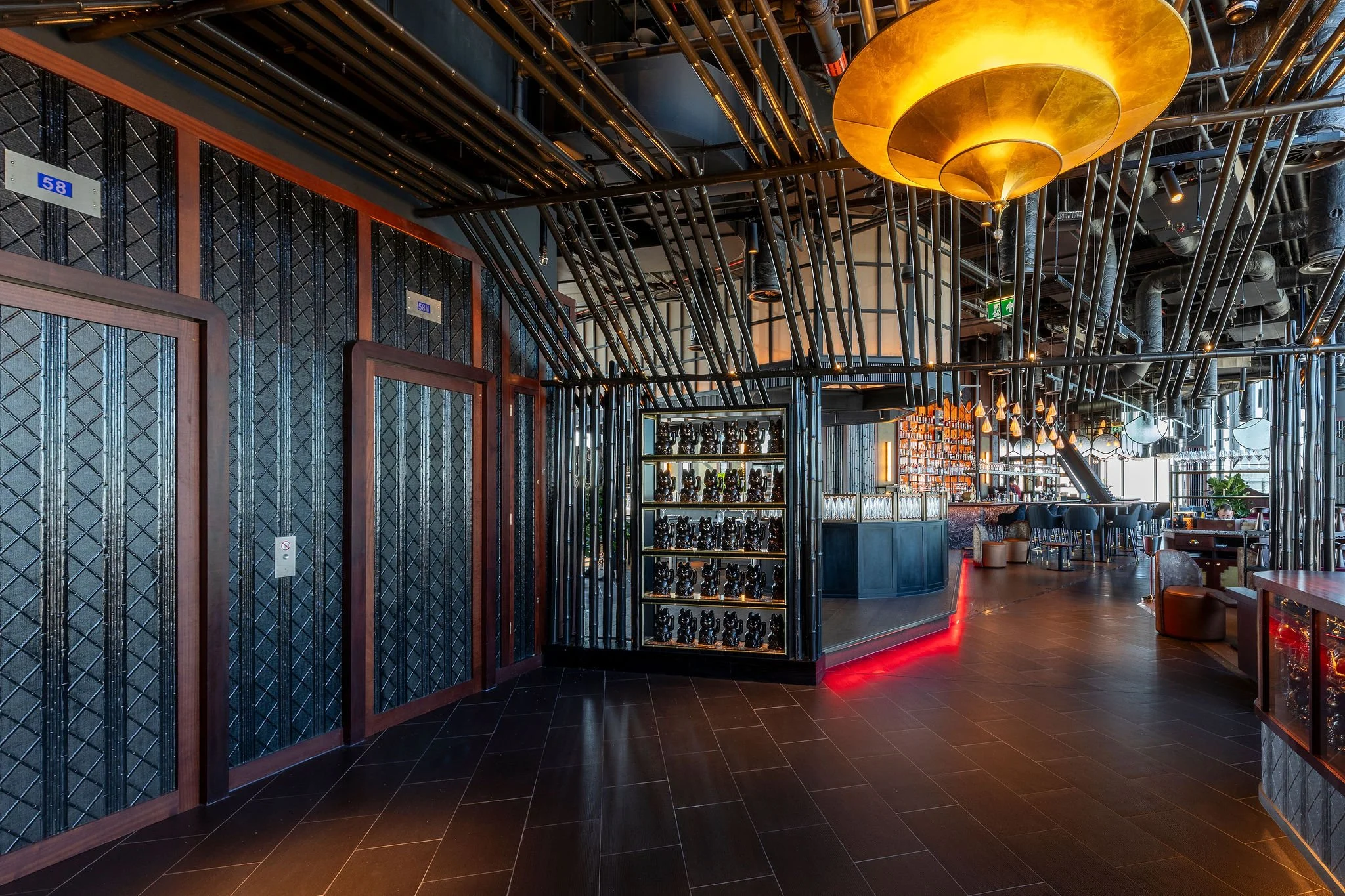 Stylish modern restaurant interior with dark wood flooring, decorative lighting, and unique black and wood wall designs.