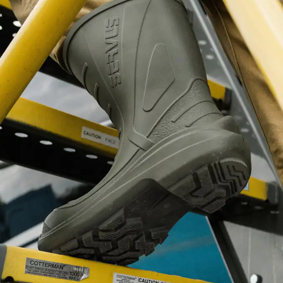 A gray work boot with the brand name 'STINGER' on the side, placed on a yellow safety ladder in a hardware store.