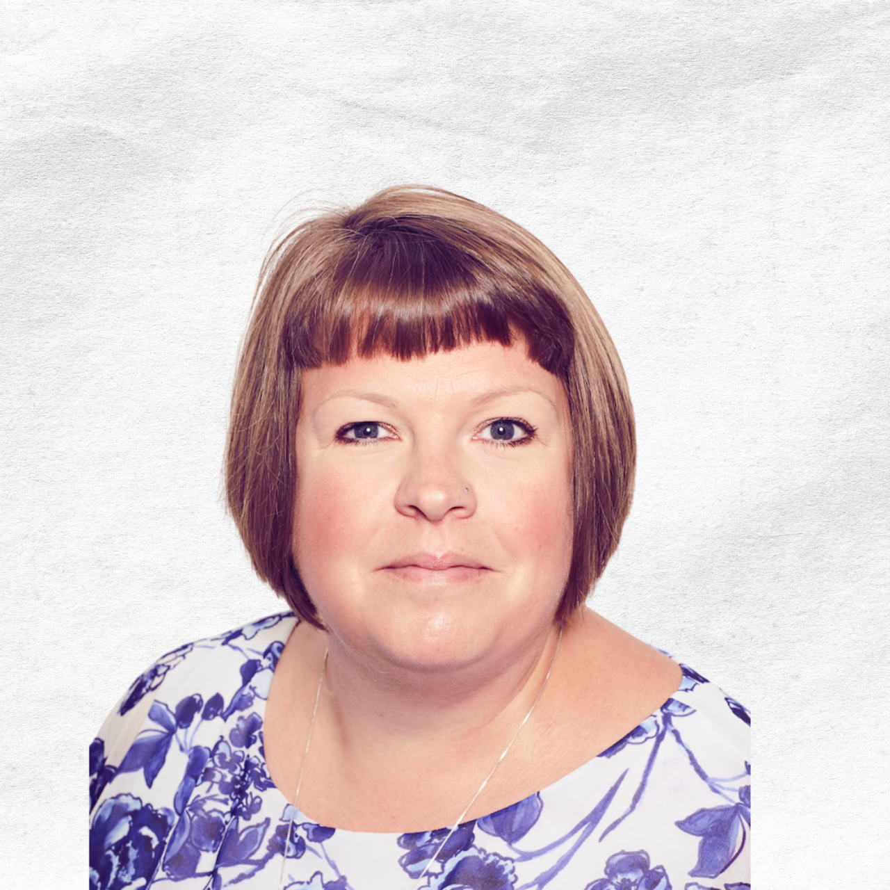 Portrait of a woman with short brown hair and blue eyes, wearing a white top with blue floral pattern.