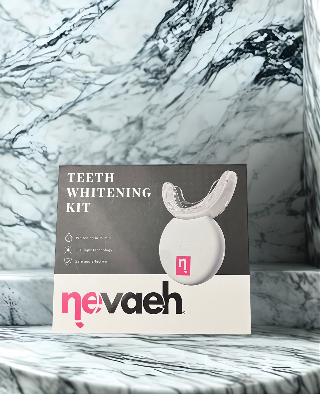 The image features a teeth whitening kit displayed against a sleek, white marble background. The product packaging is centered and shows a modern, minimalist design. The front of the box includes a photo of the LED mouth tray device along with a list