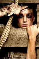 mujer con magulladuras atada con una cuerda a un madero