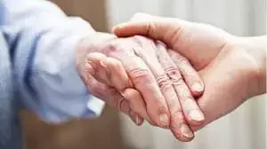 Las manos sostienen a la mano del anciano, acompañándole y sosteniéndole