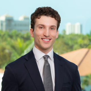 Woman sitting on a bench, writing in a notebook in a minimalist room with wooden wall panels and an abstract artwork leaning against the wall.