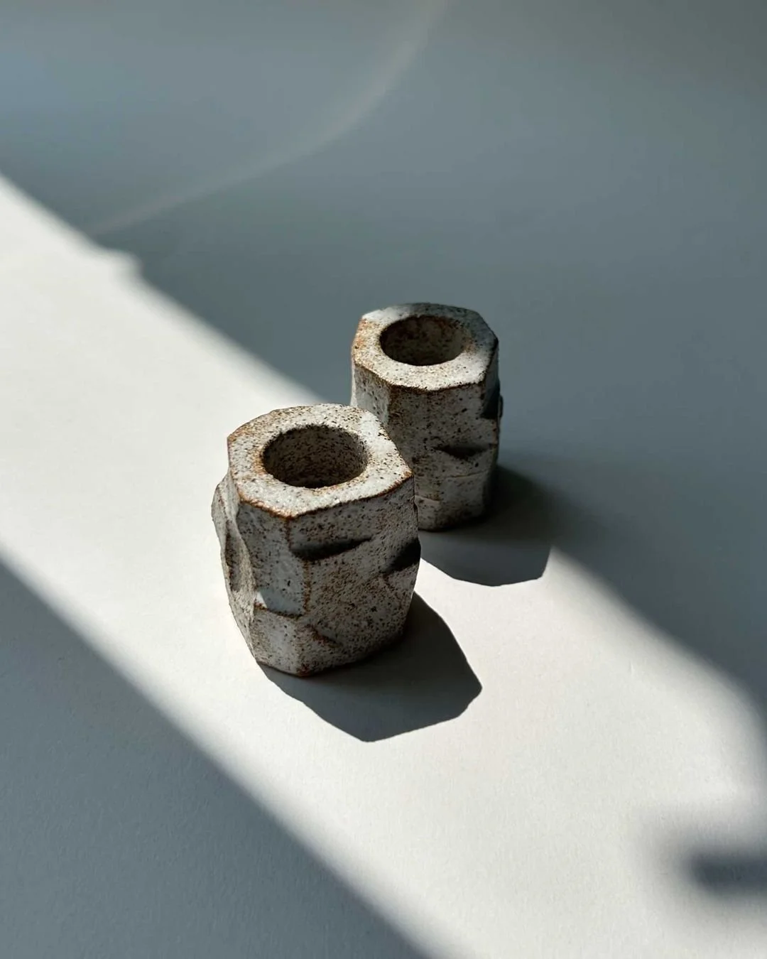 Set of Two Candle Holders N. II

Hand built in chamote light brown sandstone clay, these candle holders are made by Gabriela Bins in Lisbon, Portugal. Finished in a matte white glaze, the surface reveals the rugged texture of the clay and the marks o