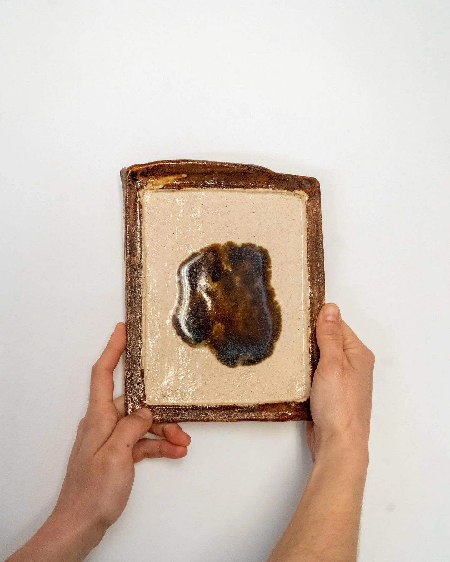 Glossy Earth is handbuilt by Kelly Begiazi in Barcelona. A stoneware frame finished in a dark honey glaze showcases a wild clay piece sourced from the city, fired at 1250&deg;. A unique piece that invites appreciation of the land as it is, and of the