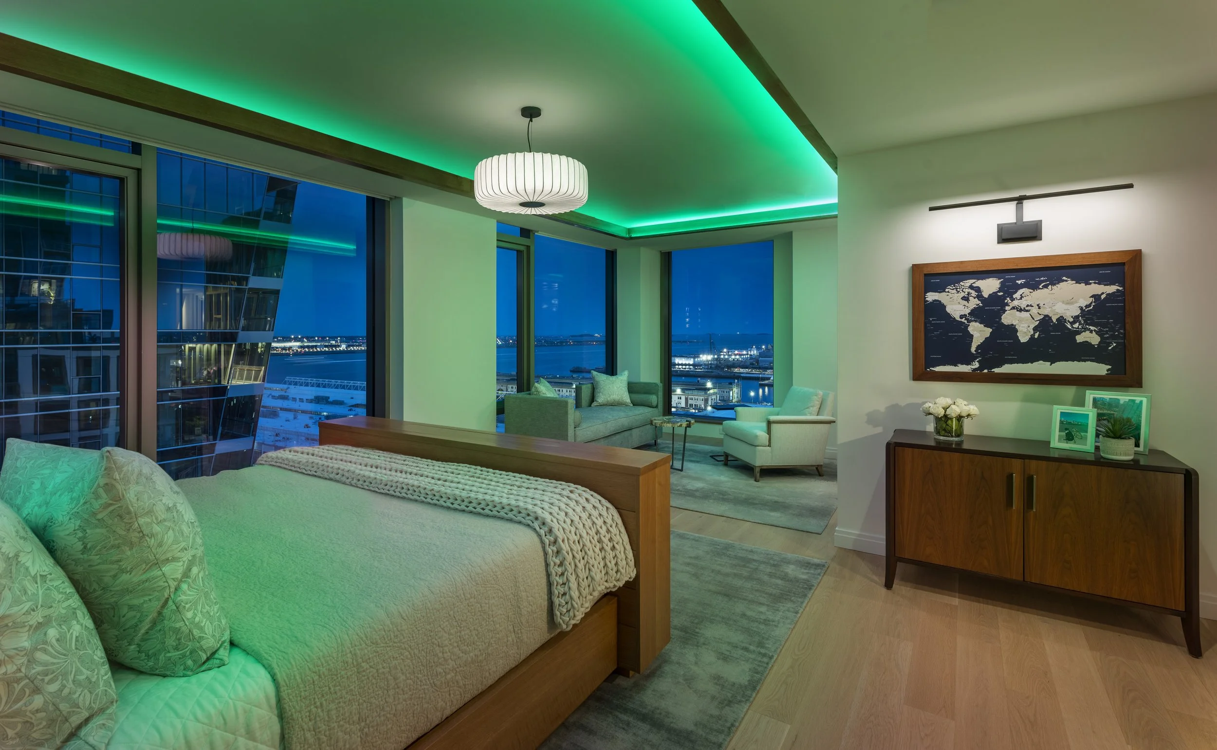Primary bedroom with green LED cove lighting, rift-oak ceiling detail, custom floating bed, and harbor views.