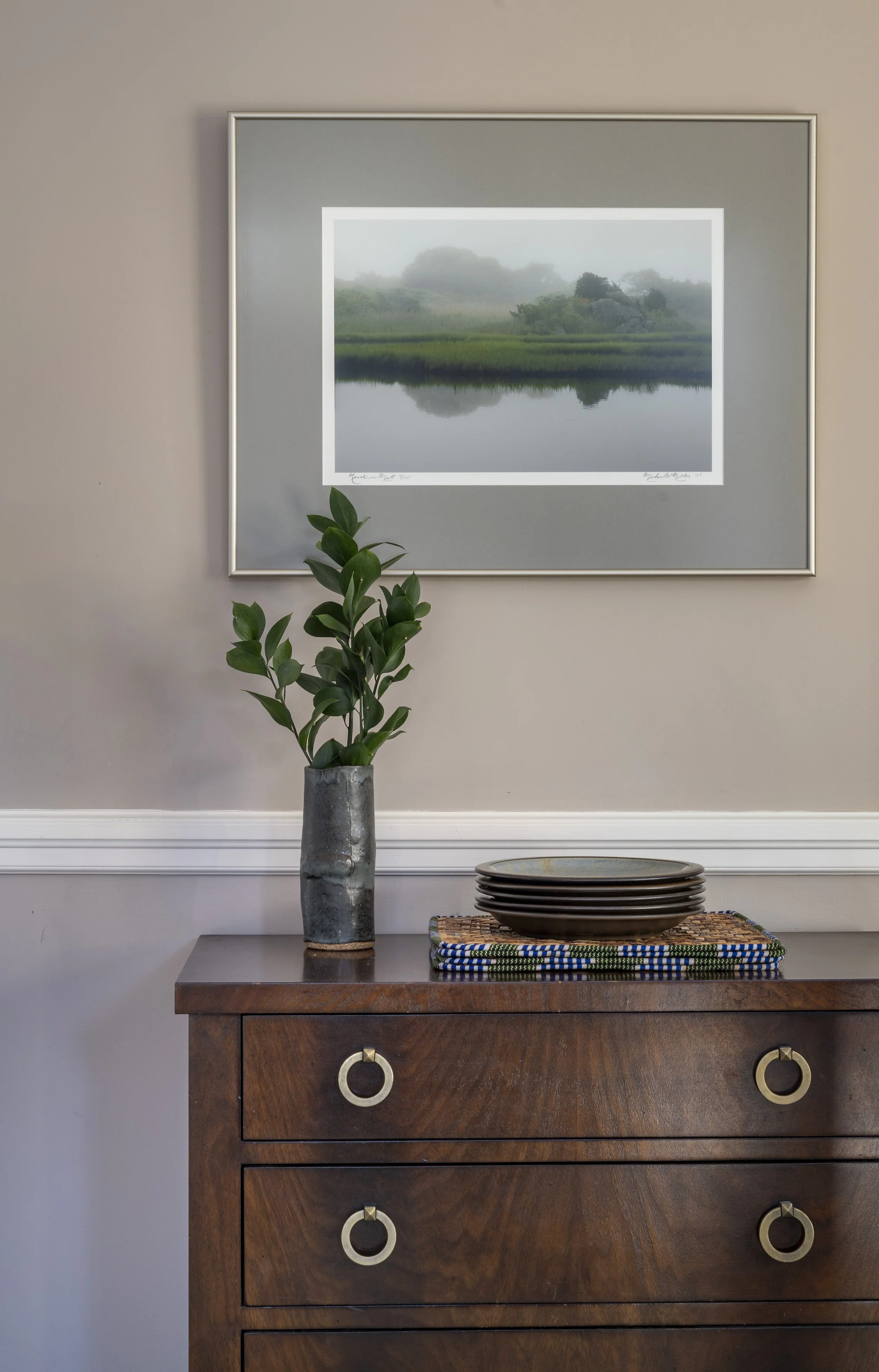 Dining room detail in the Cambridge home designed by AbbeyK showing a vintage sideboard styled with pottery and a framed green landscape artwork.
