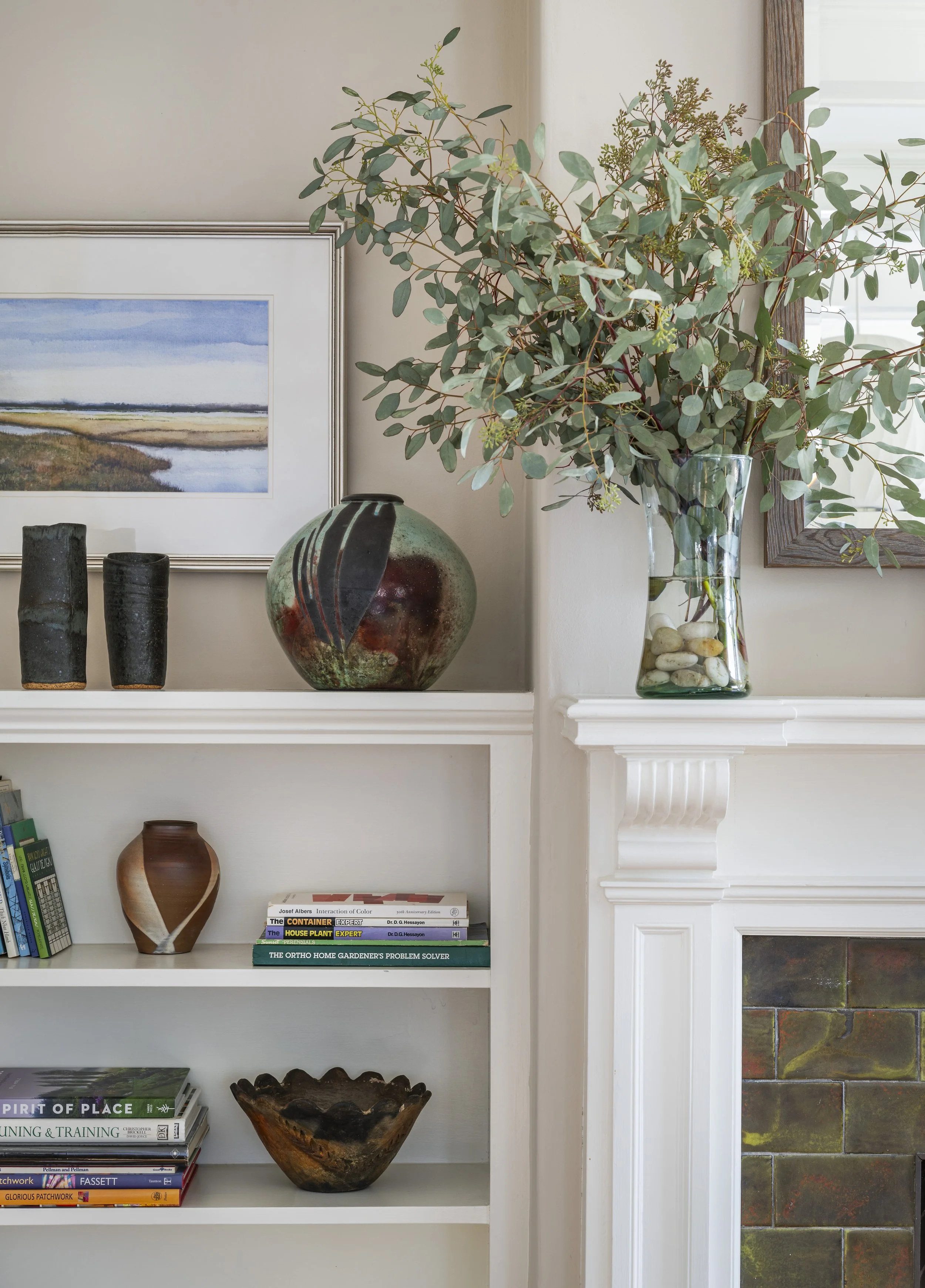 Cambridge living room with a built-in bookcase and fireplace surround styled with framed artwork and varied pottery, integrated into the seating area designed by AbbeyK.