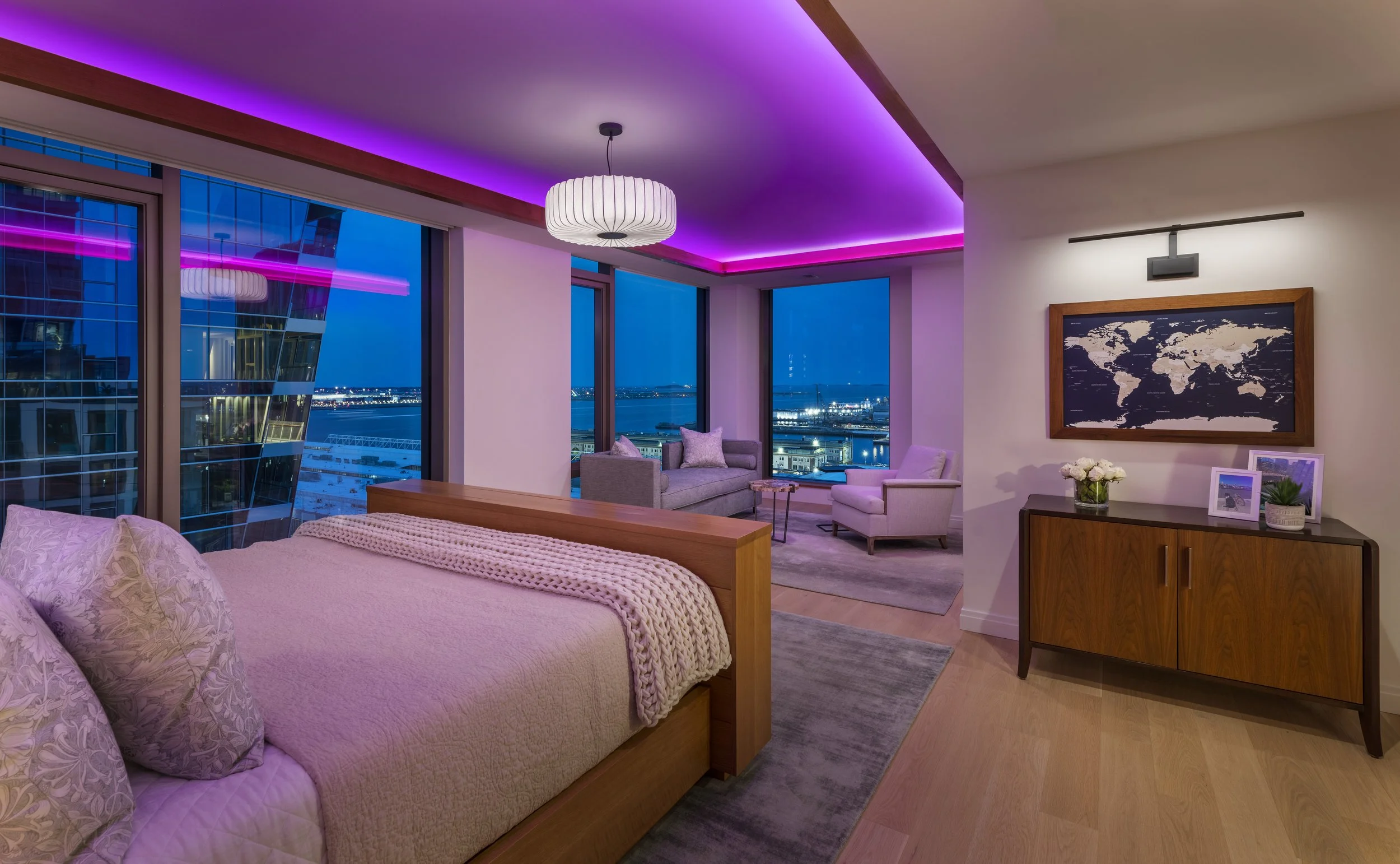 Primary bedroom with pink LED cove lighting, rift-oak ceiling detail, custom bed, and harbor views.