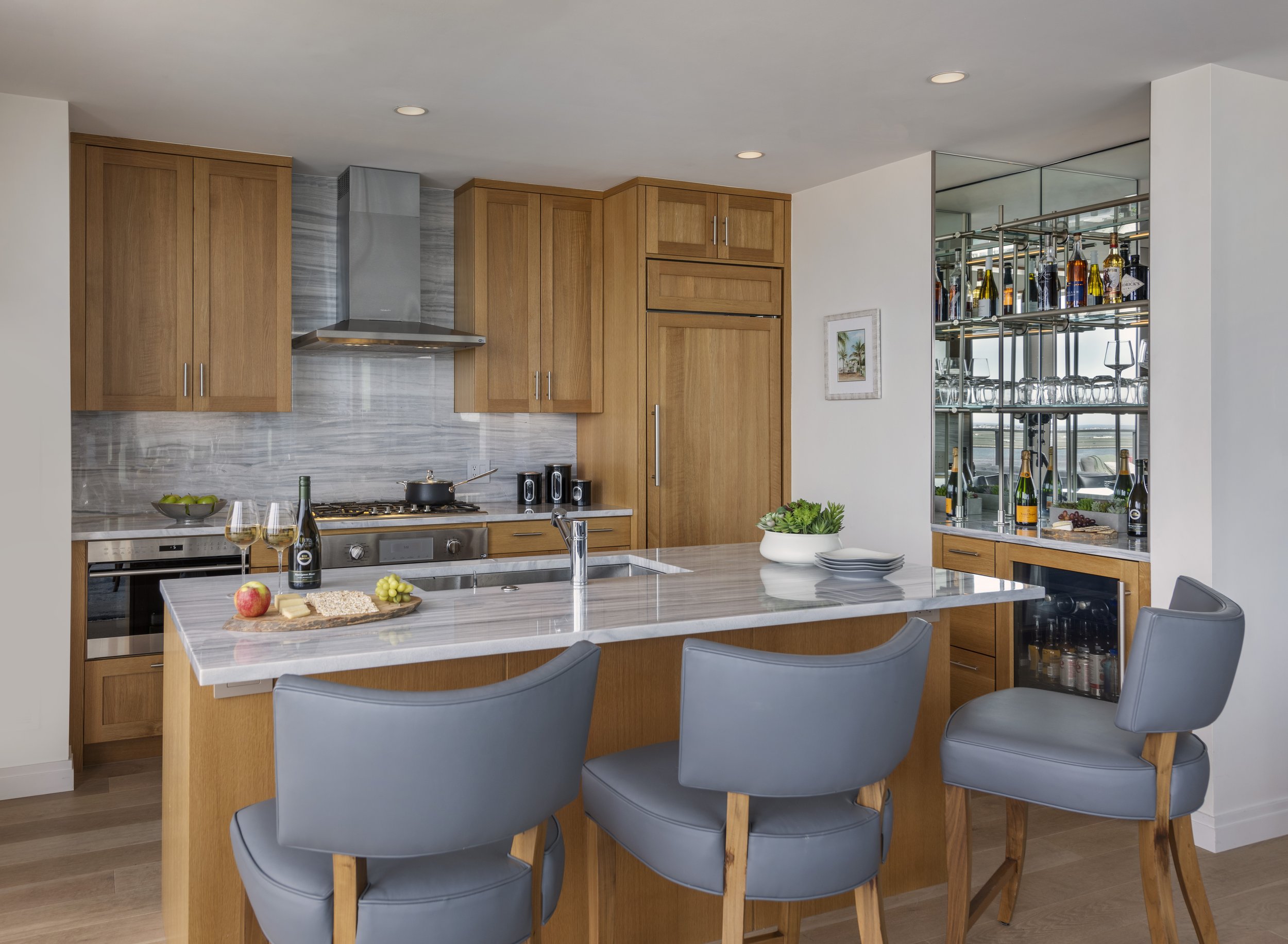 Seaport high-end renovation kitchen with rift-oak cabinetry, nestos striée marble, leather stools, and Miele and Sub-Zero appliances. 