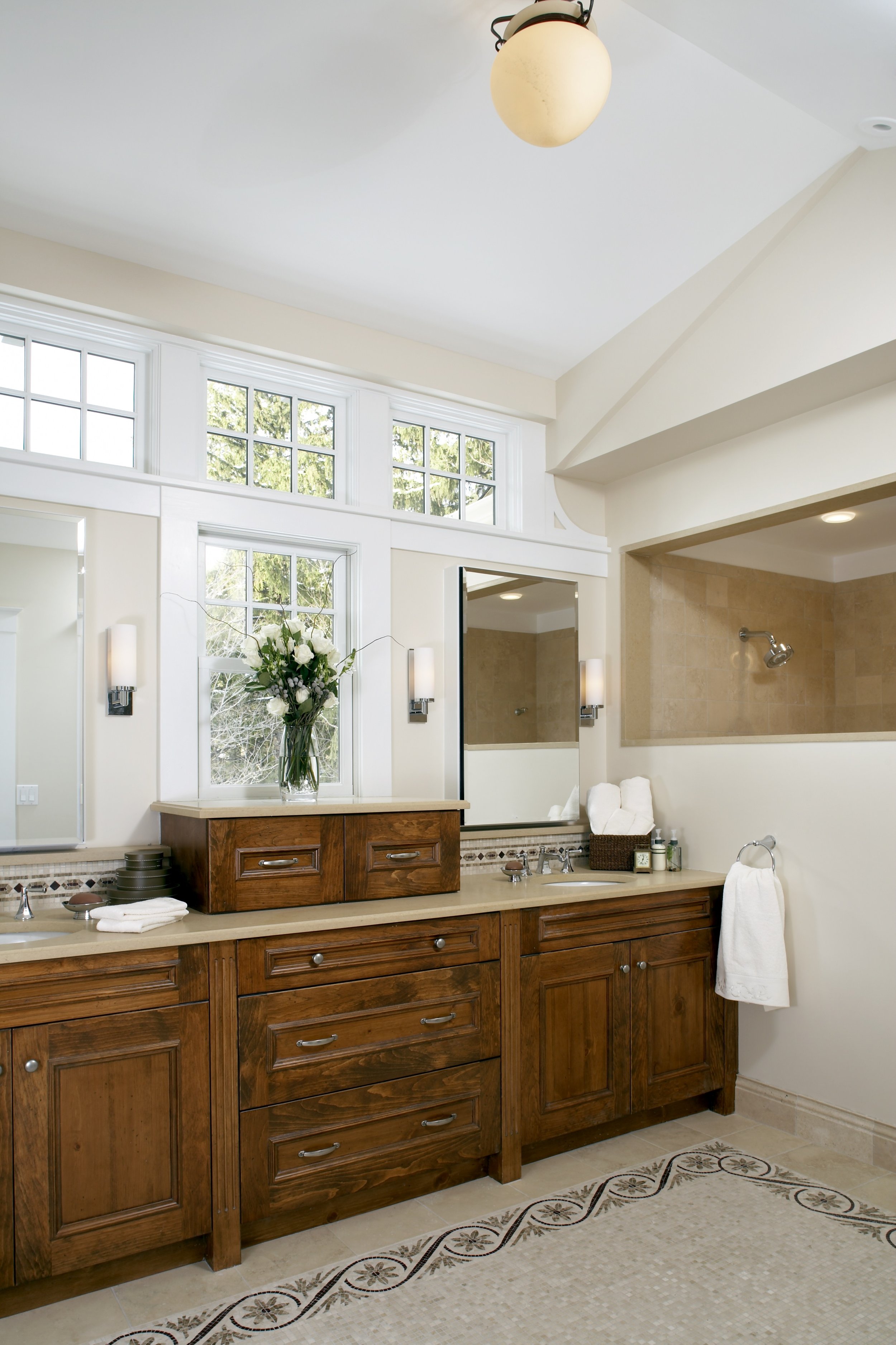 Master bathroom with custom wood vanity, double sinks, and transom windows featured on This Old House.