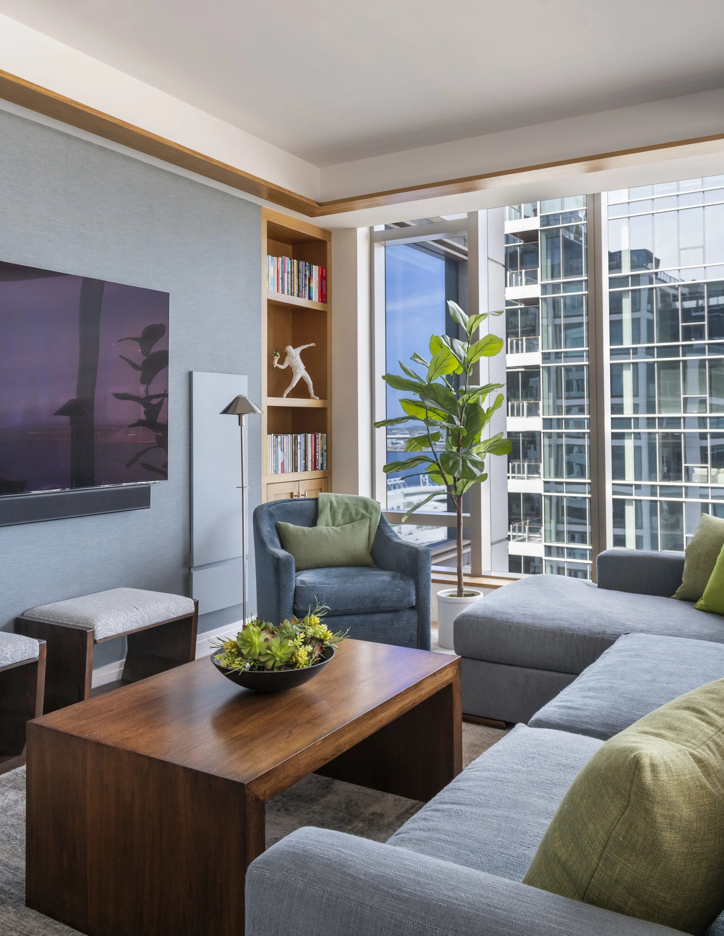 Living room detail with denim sectional, William Morris pillows, walnut waterfall table, silk rug, and rift-oak ceiling cove.