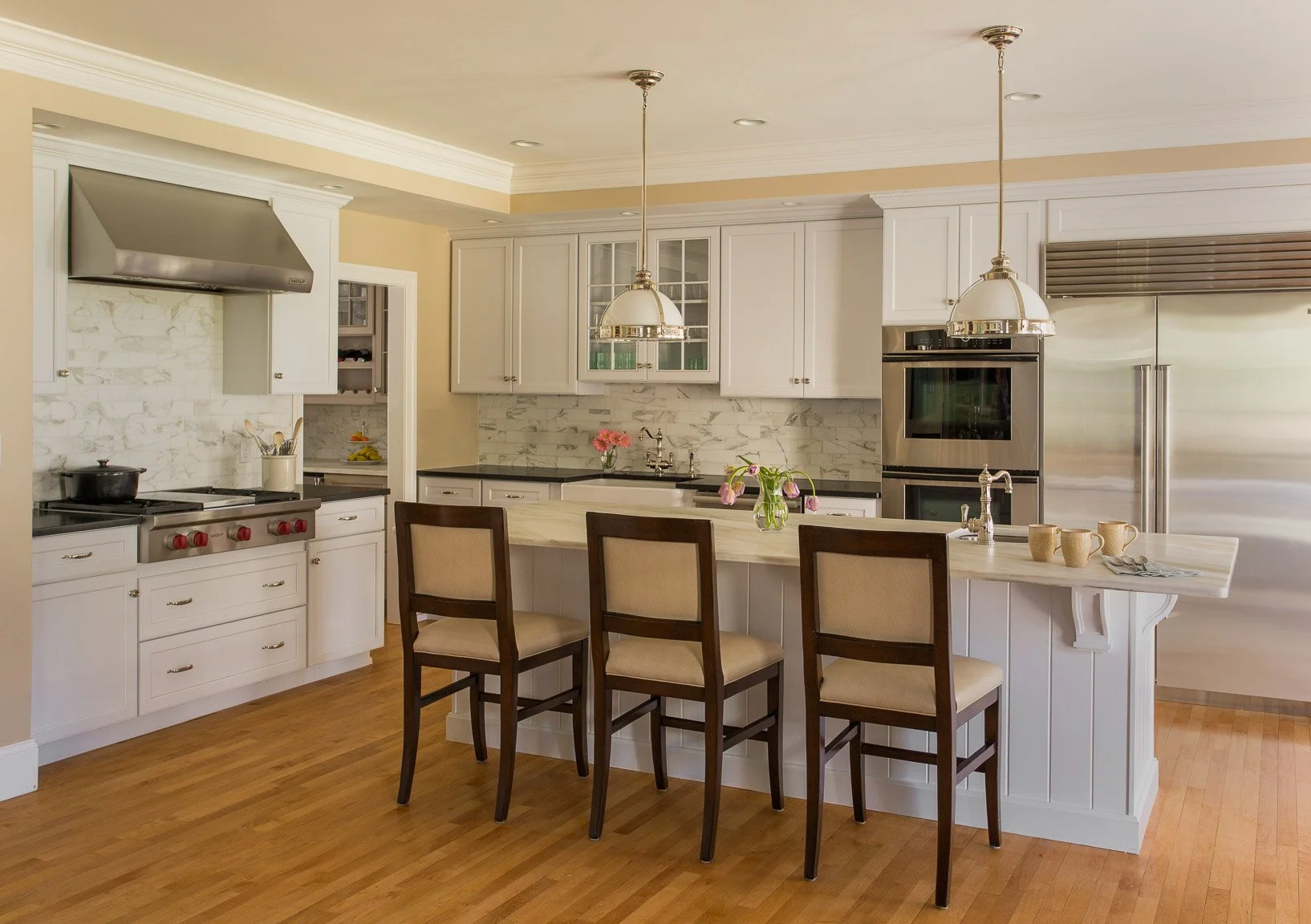 West Newton kitchen with light cabinetry, warm wood accents, simple backsplash, and pendant lighting.
