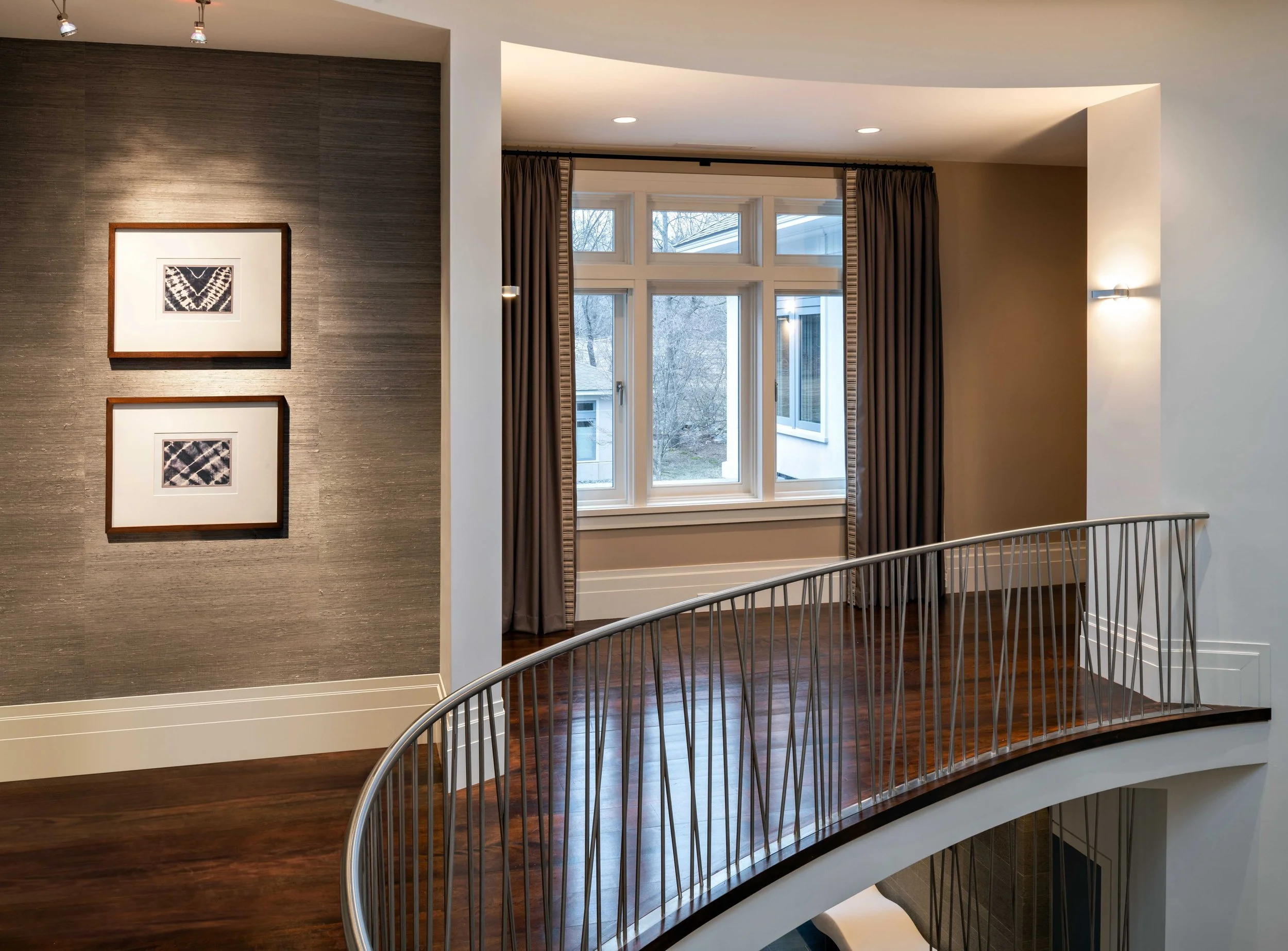 Lincoln upper hallway with repeating grass cloth wallpaper and drapery colors, walnut floors, and sleek chrome metal railing.