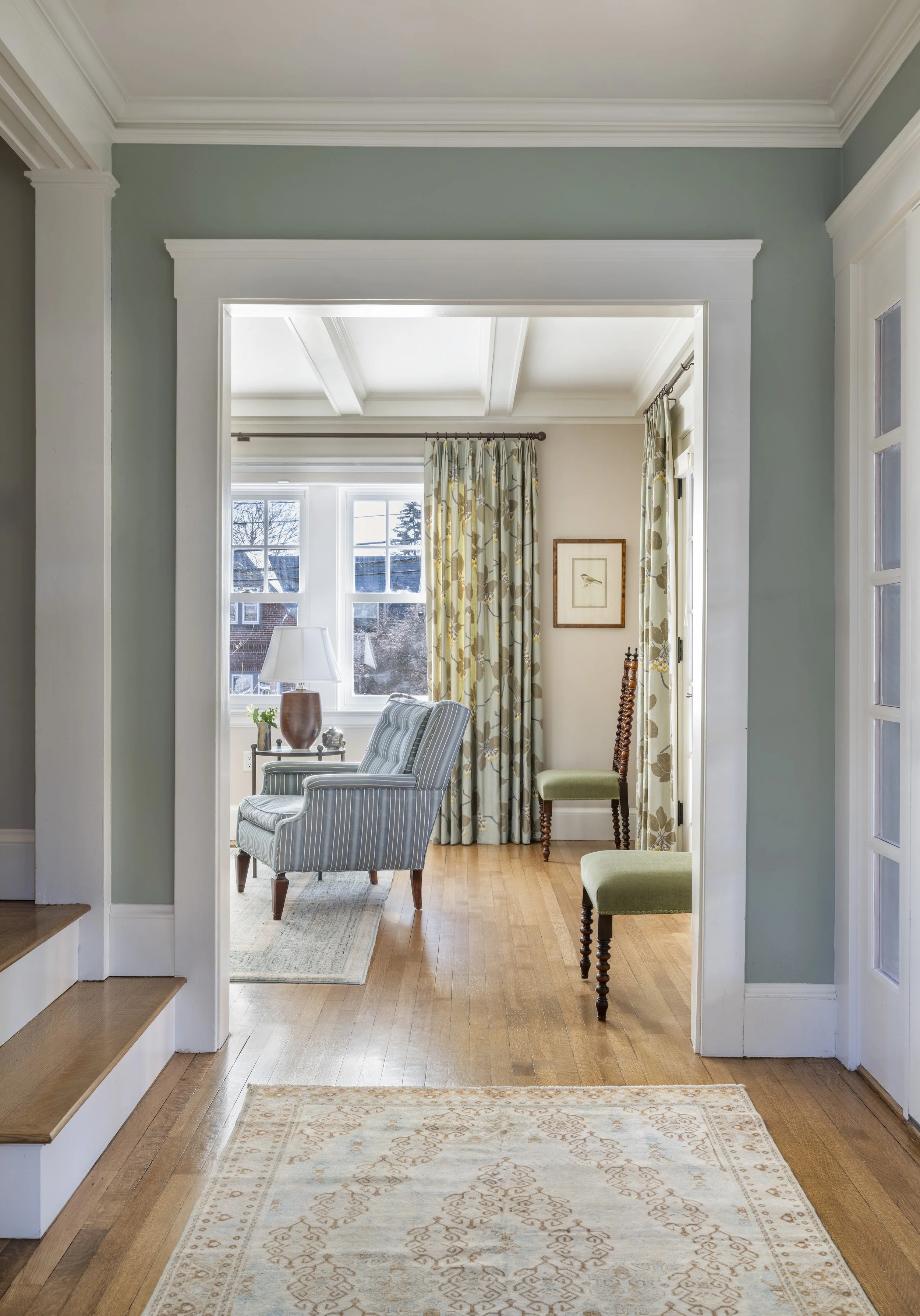Cambridge hallway with vintage Persian runner, framed art, and view into living room with patterned window treatments, by AbbeyK