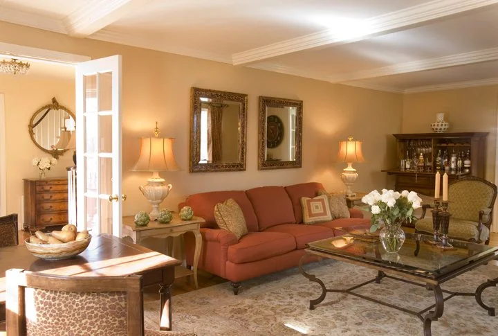 West Newton living room with rust sofa, glass-top coffee table, carved wood side tables, and custom bar cabinet.