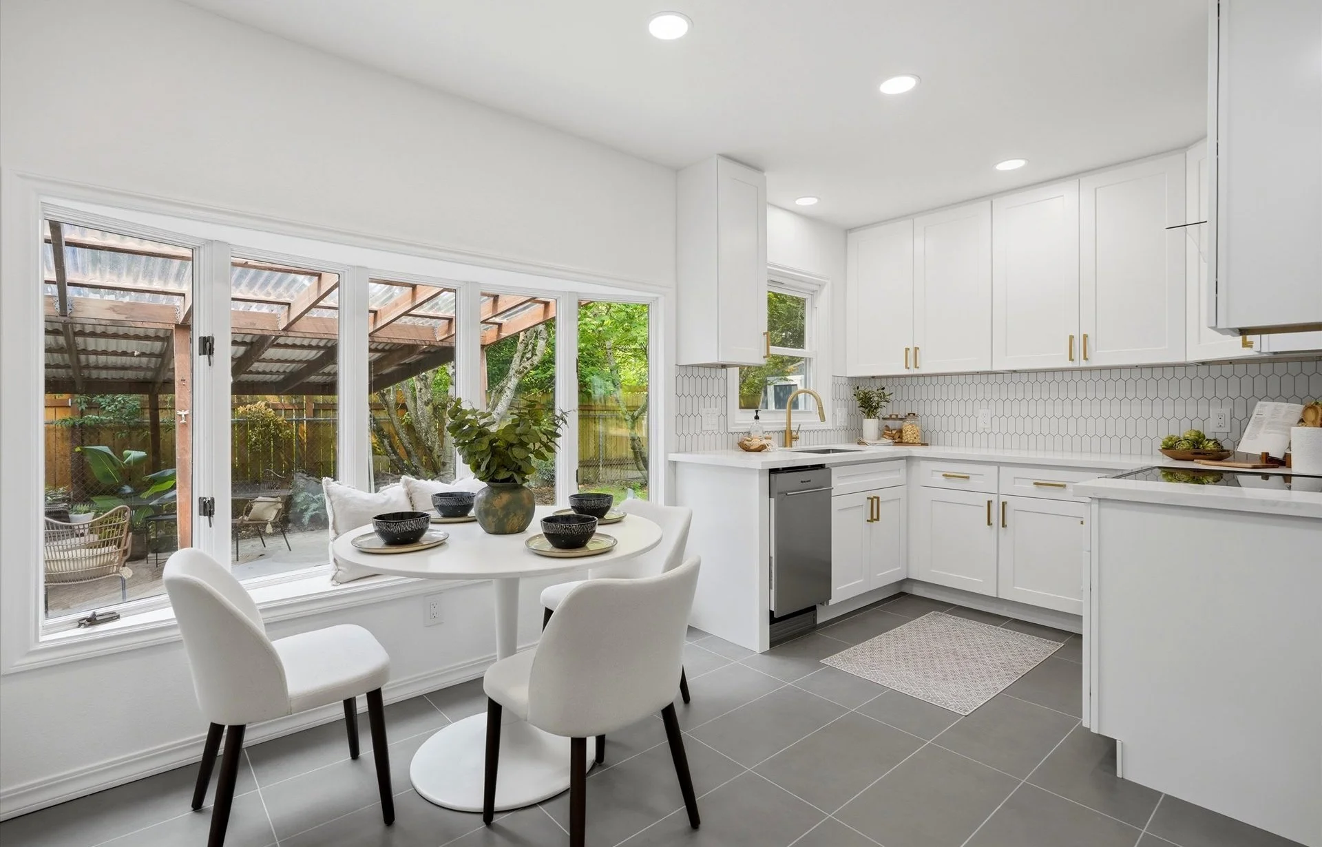 Remodeled kitchen with white cabinetry, quartz countertops, stainless steel appliances, and tile flooring.