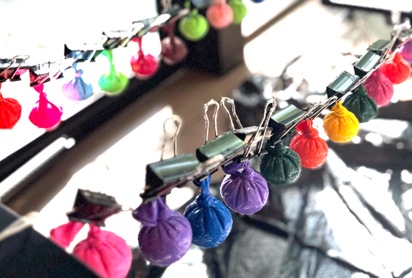 Colorful miniature umbrellas hanging on a string with clothespins, arranged in a rainbow pattern.