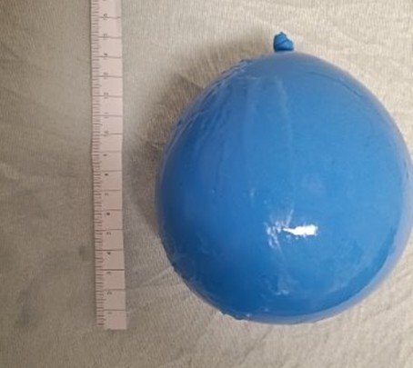 Blue balloon next to a ruler on a light-colored surface.