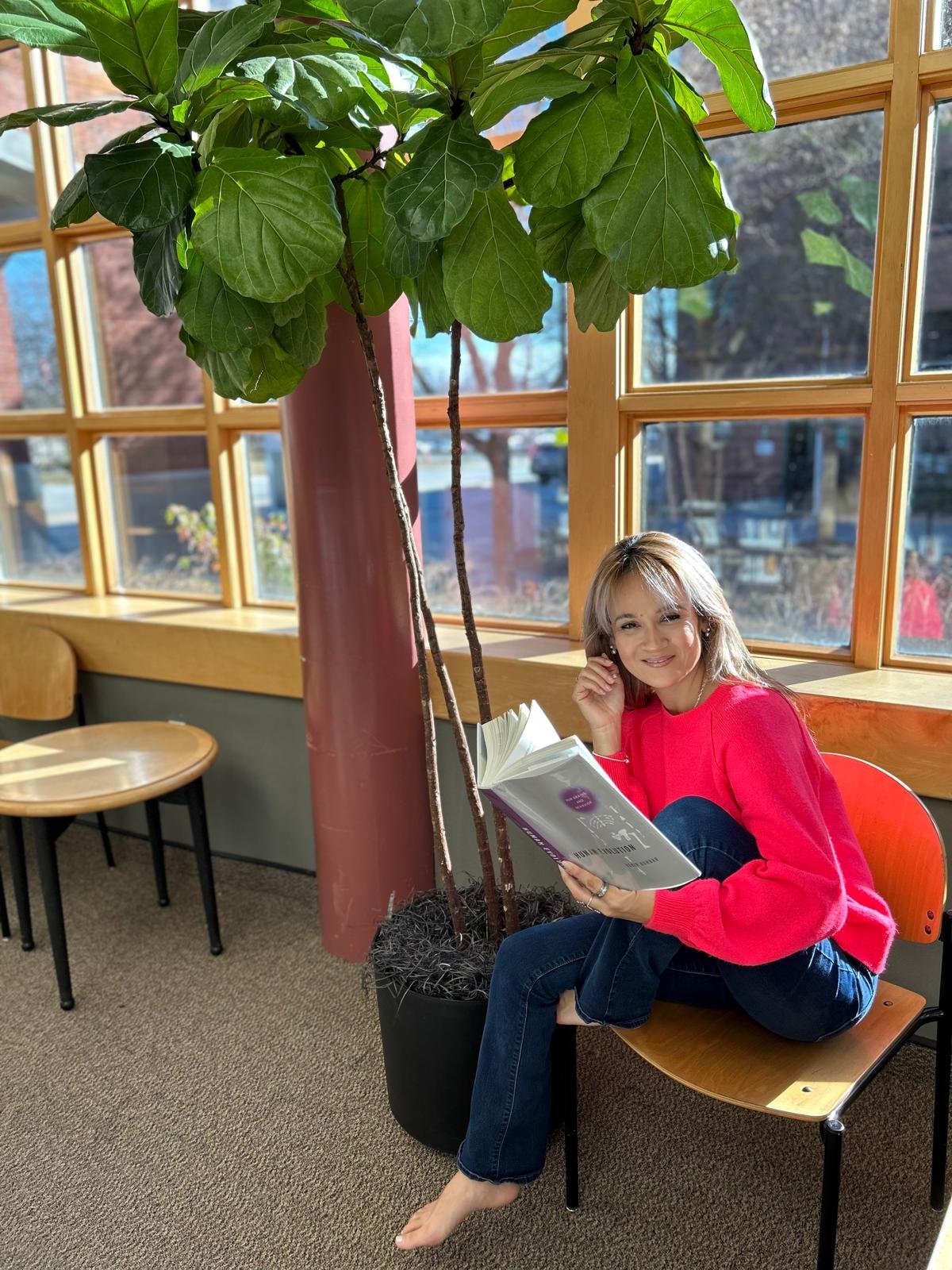A woman named Patricia sitting in a chair, deeply engaged in reading a book.