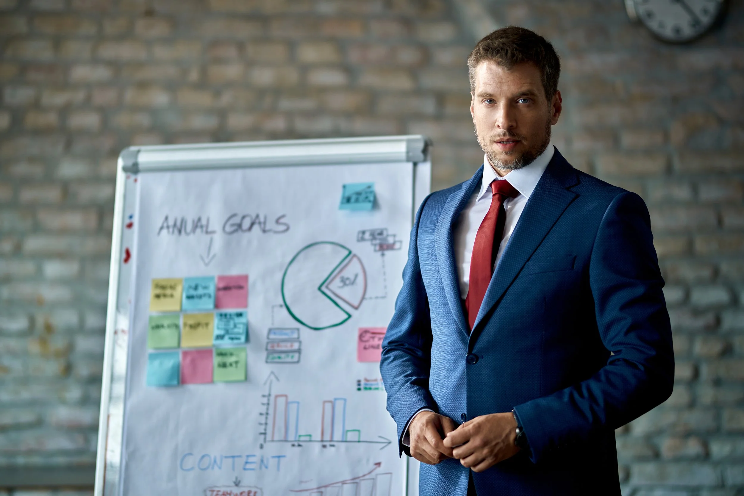 mid-adult-manager-holding-business-presentation-looking-camera-while-standing-front-whiteboard.jpg