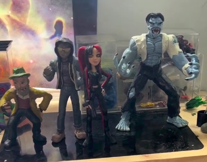 Four action figures displayed on a surface, including a character with a green hat, a figure with dreadlocks, a female character with red and black hair, and a large blue monster with sharp teeth, wearing a vest.