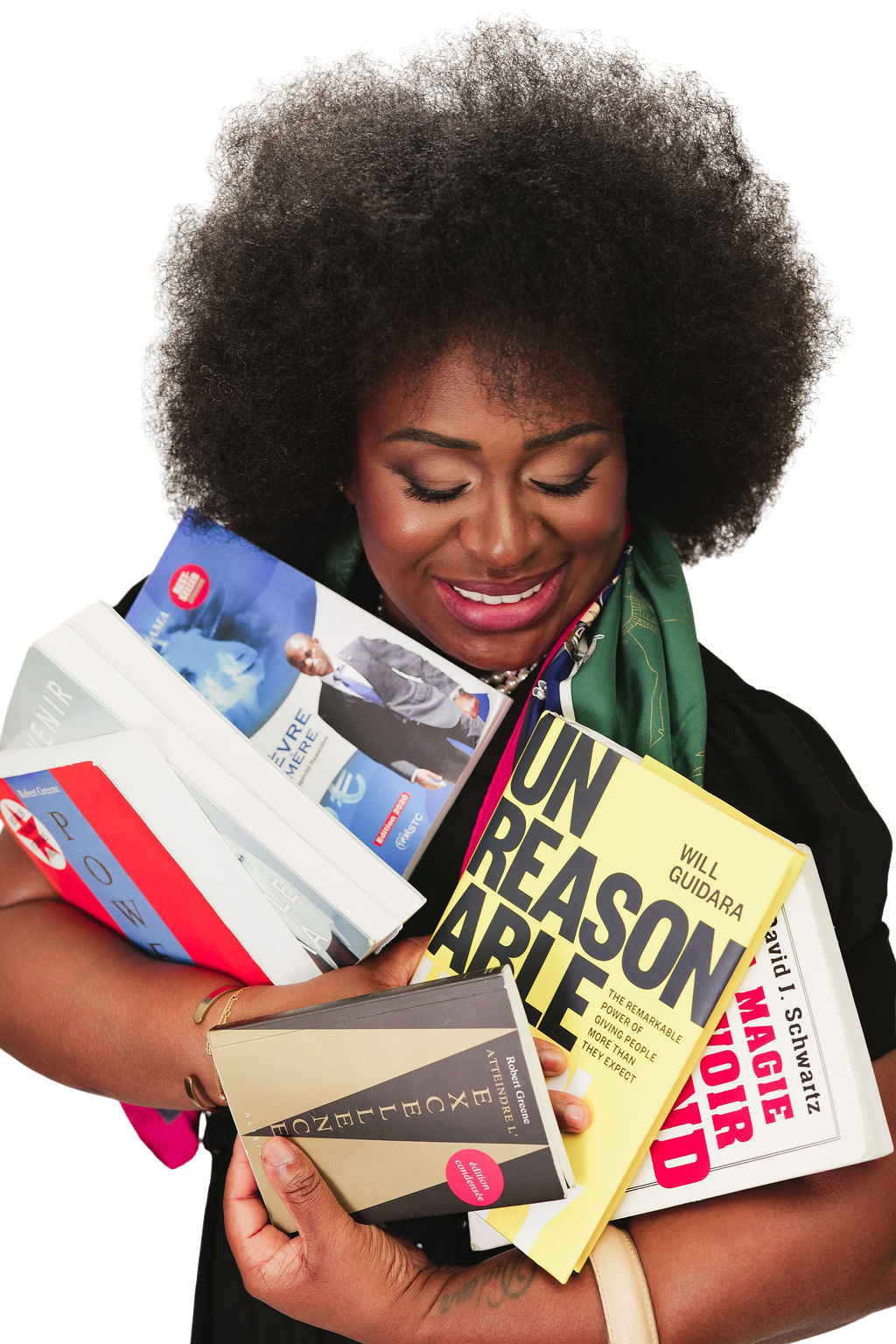 A woman with curly black hair smiling and looking down at several books she is holding.