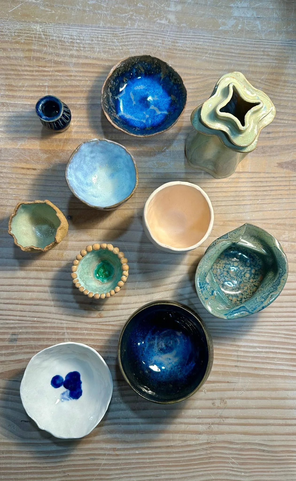 Différents petits bols en céramique colorés et décorés, disposés sur une surface en bois.