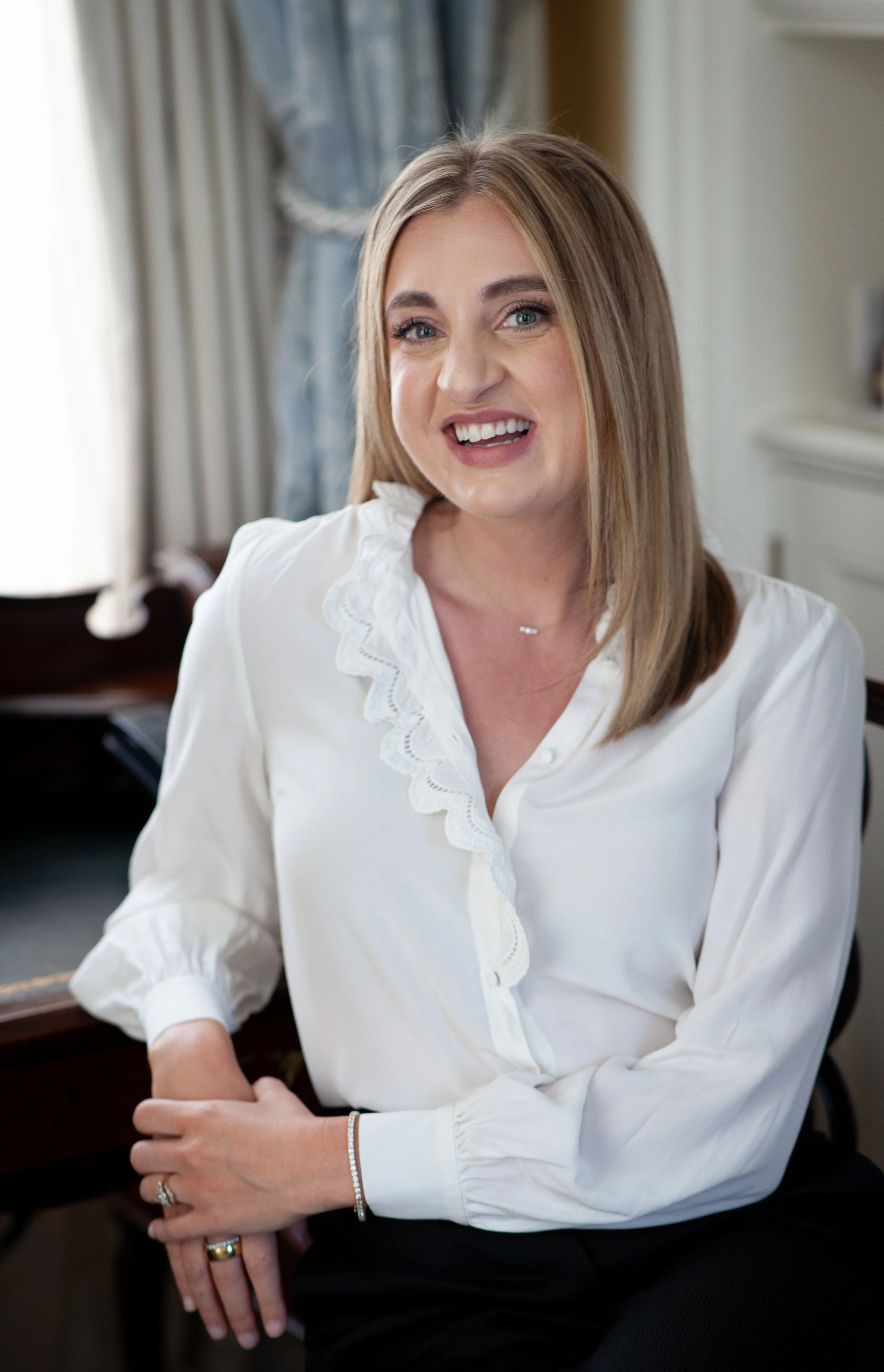 Whitney Haldeman, the founder of Atlas Adventures, smiling and sitting indoors near a window.