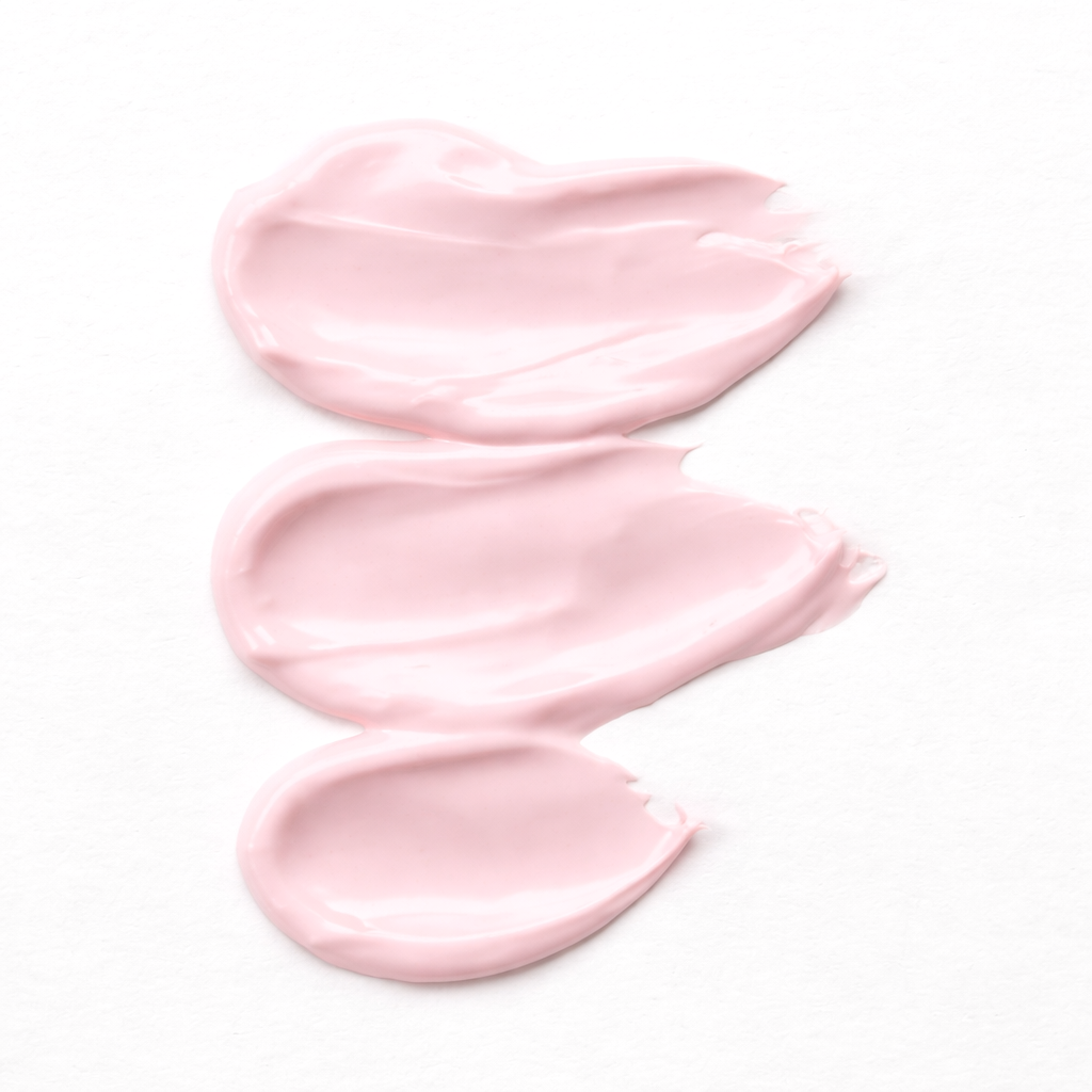 Three swatches of light pink cream or lotion on a white background
