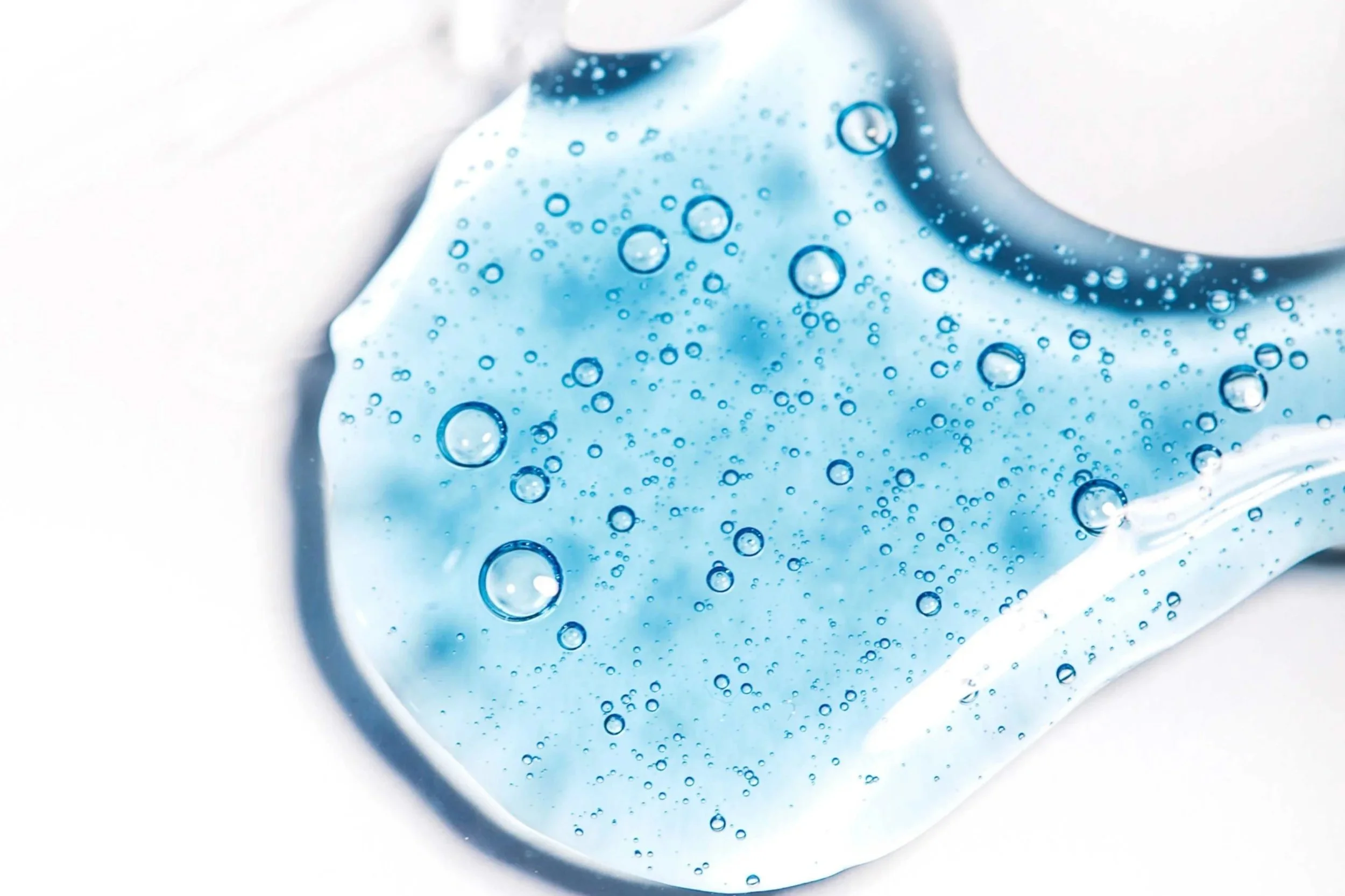 Close-up of a thermometer with a blue liquid inside, showing temperature measurement with bubbles visible in the liquid.