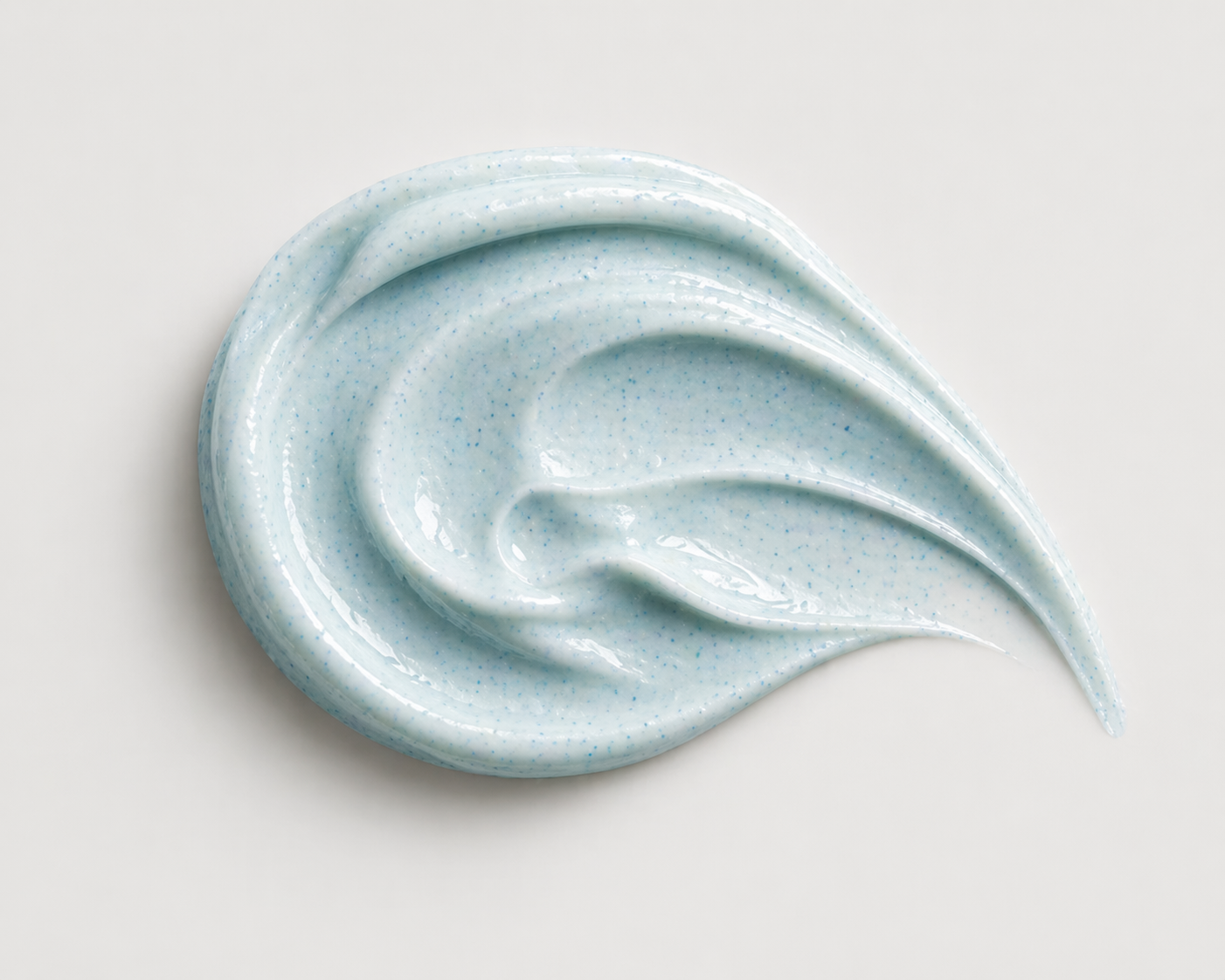 A swirl of light blue cream with darker blue speckles, shaped like a leaf or wave, on a white background.