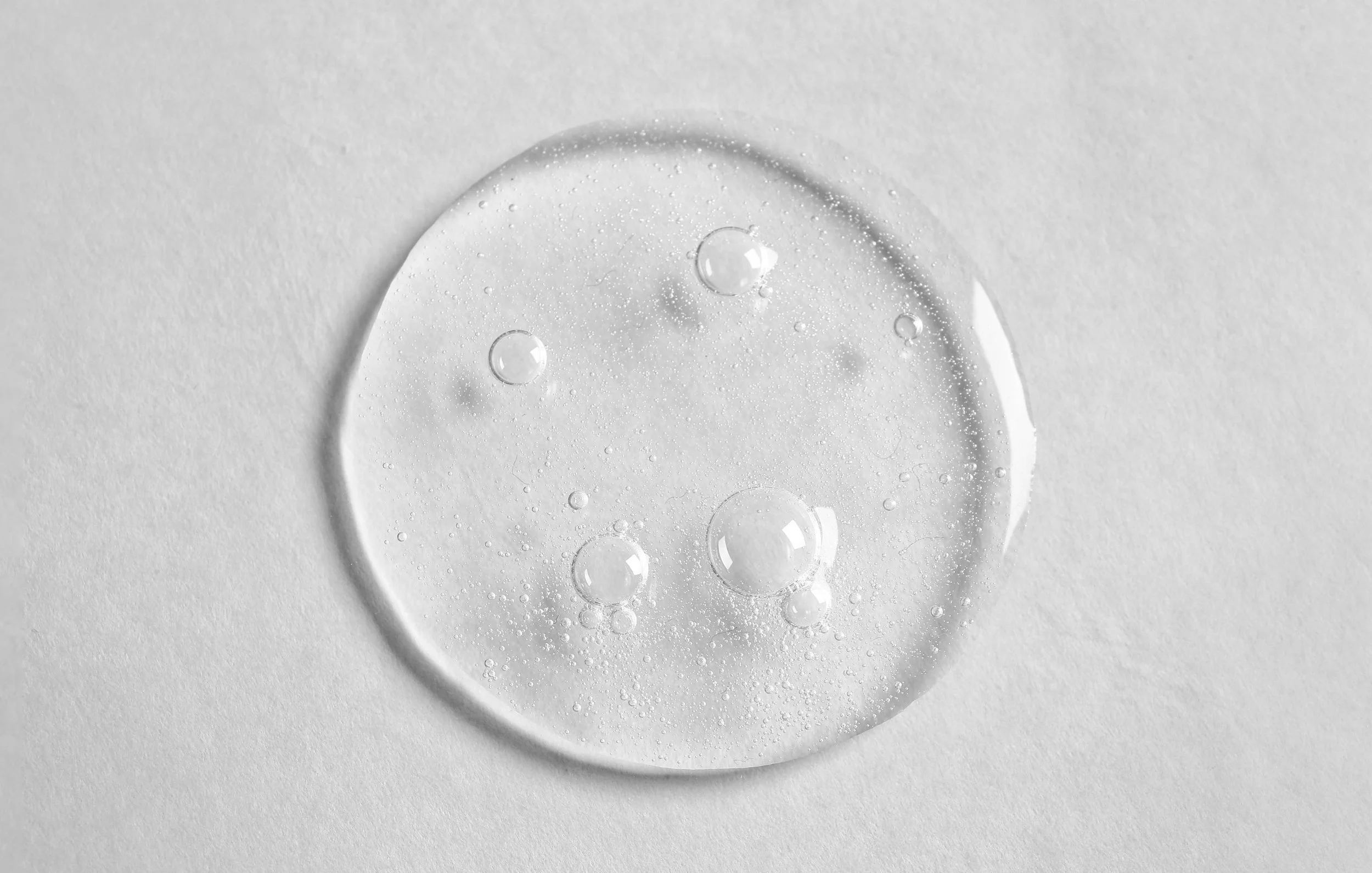 Close-up of a clear droplet of water on a white surface.