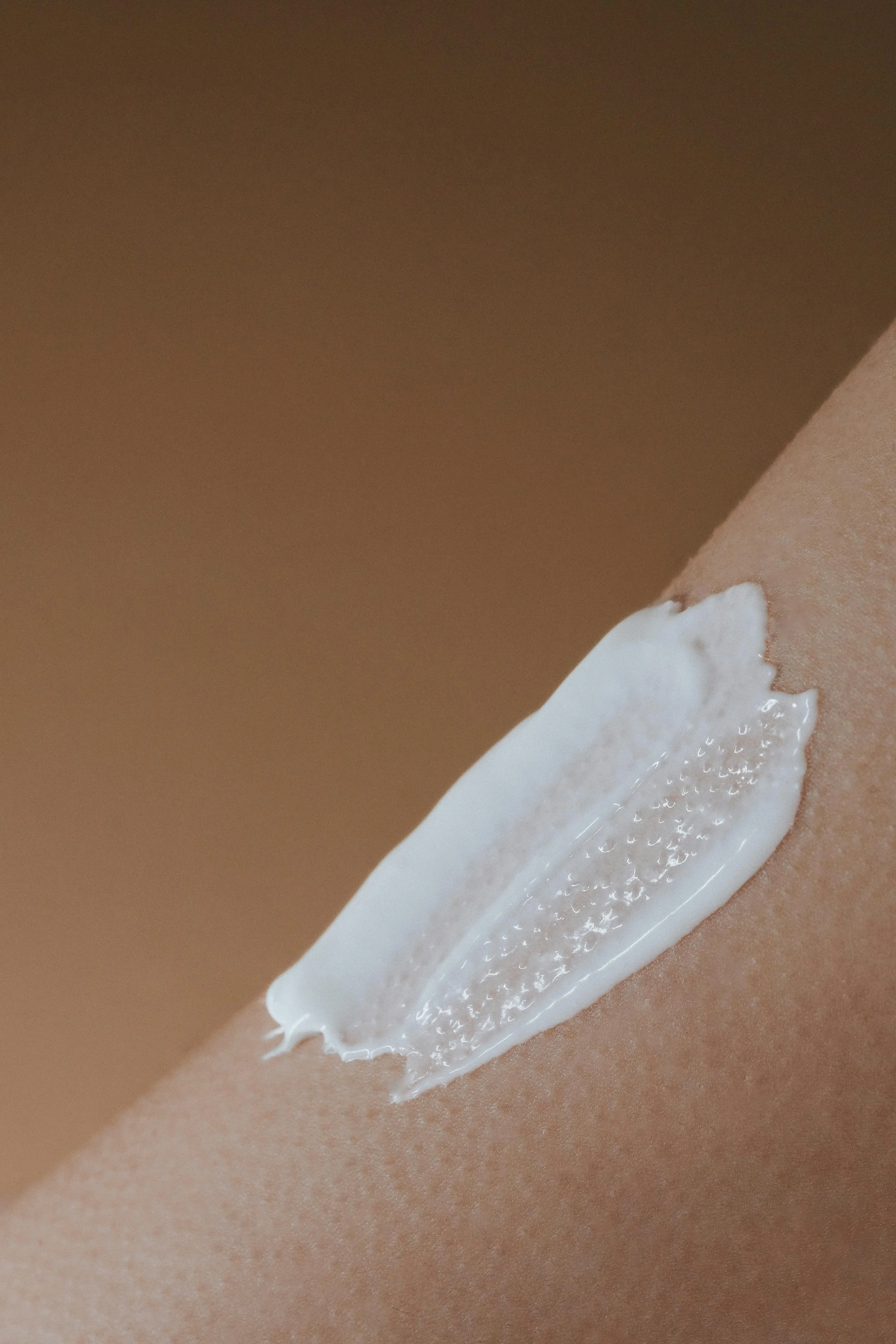 A dollop of white lotion or cream applied on a person's skin, possibly on the arm.