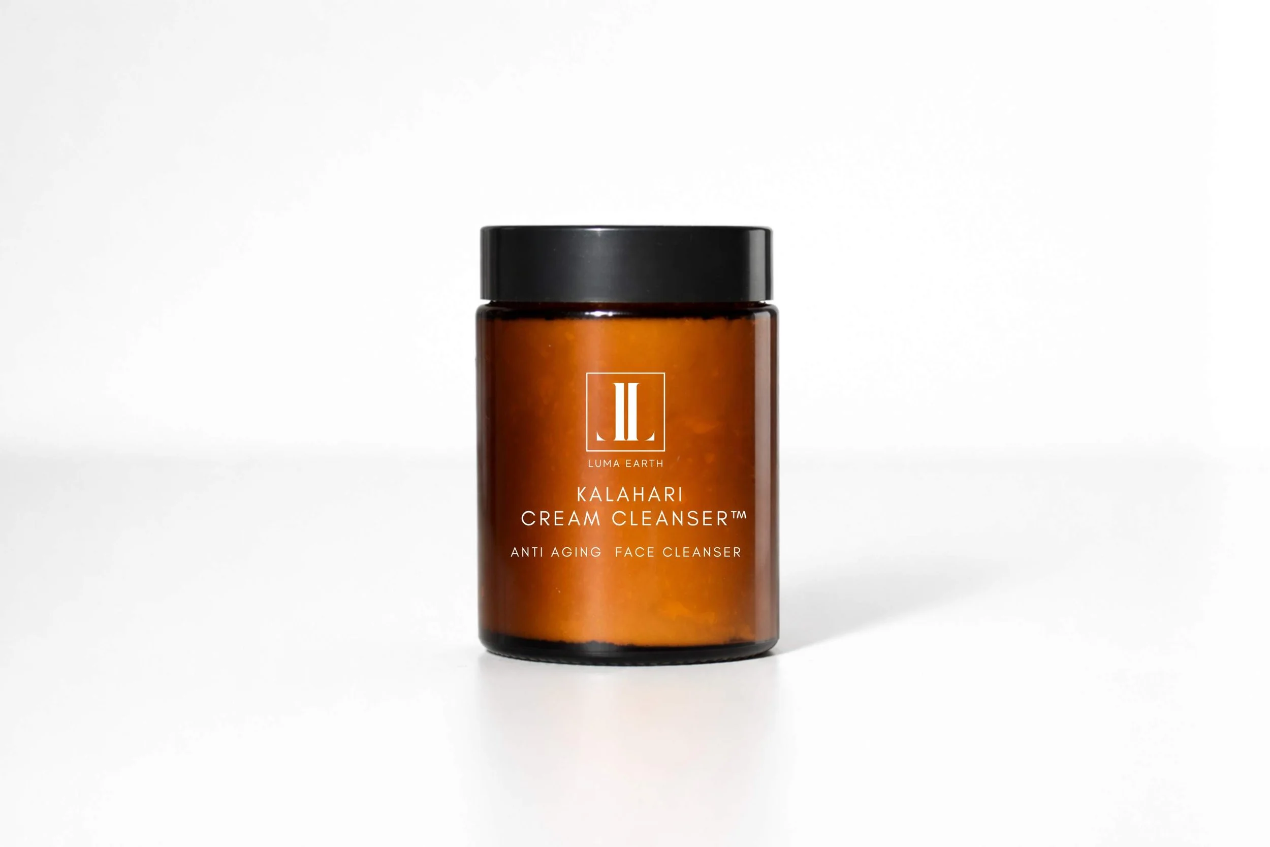 Amber glass jar with black lid labeled 'Luma Earth Kalahari Cream Cleanser, Anti Aging Face Cleanser' on a white background.