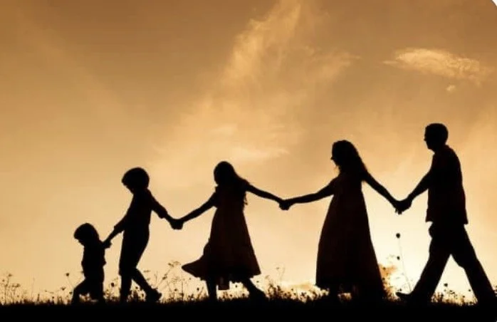 Silhouettes of a family holding hands and walking together outdoors during sunset with light of life birth doula near me in bryan and college station tx.