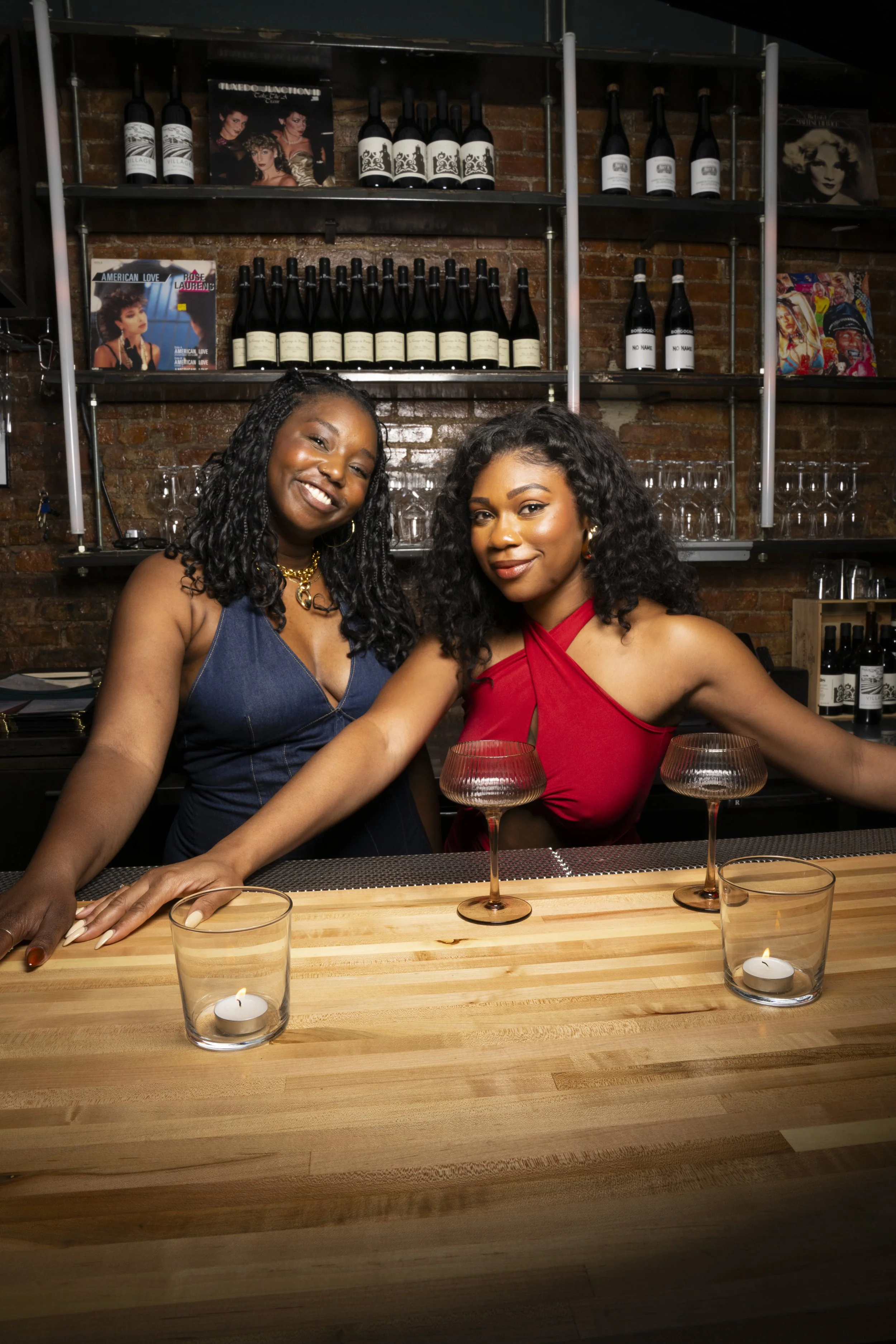 Two women standing behind a bar and smiling