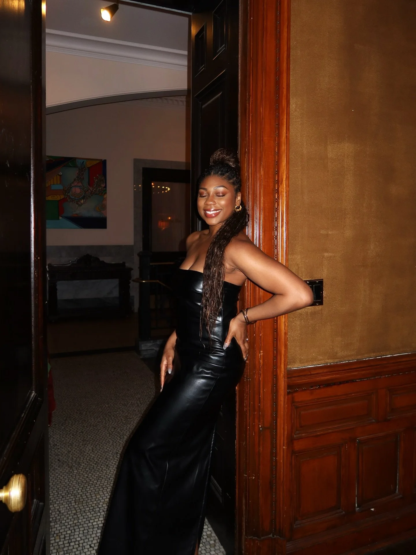 Woman in black dress leaning against wall and smiling