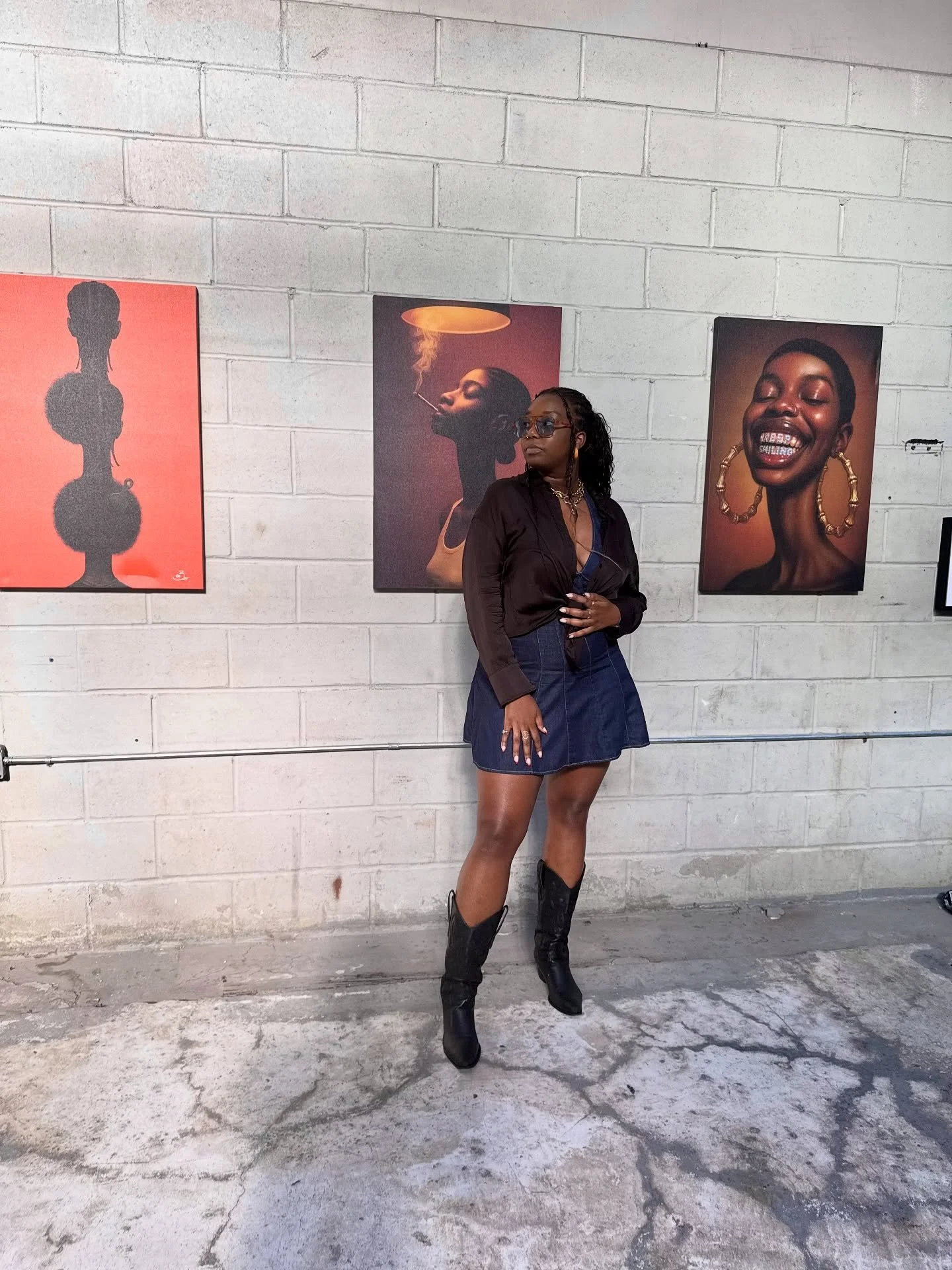 Woman standing in photo gallery in blue denim dress with a black top