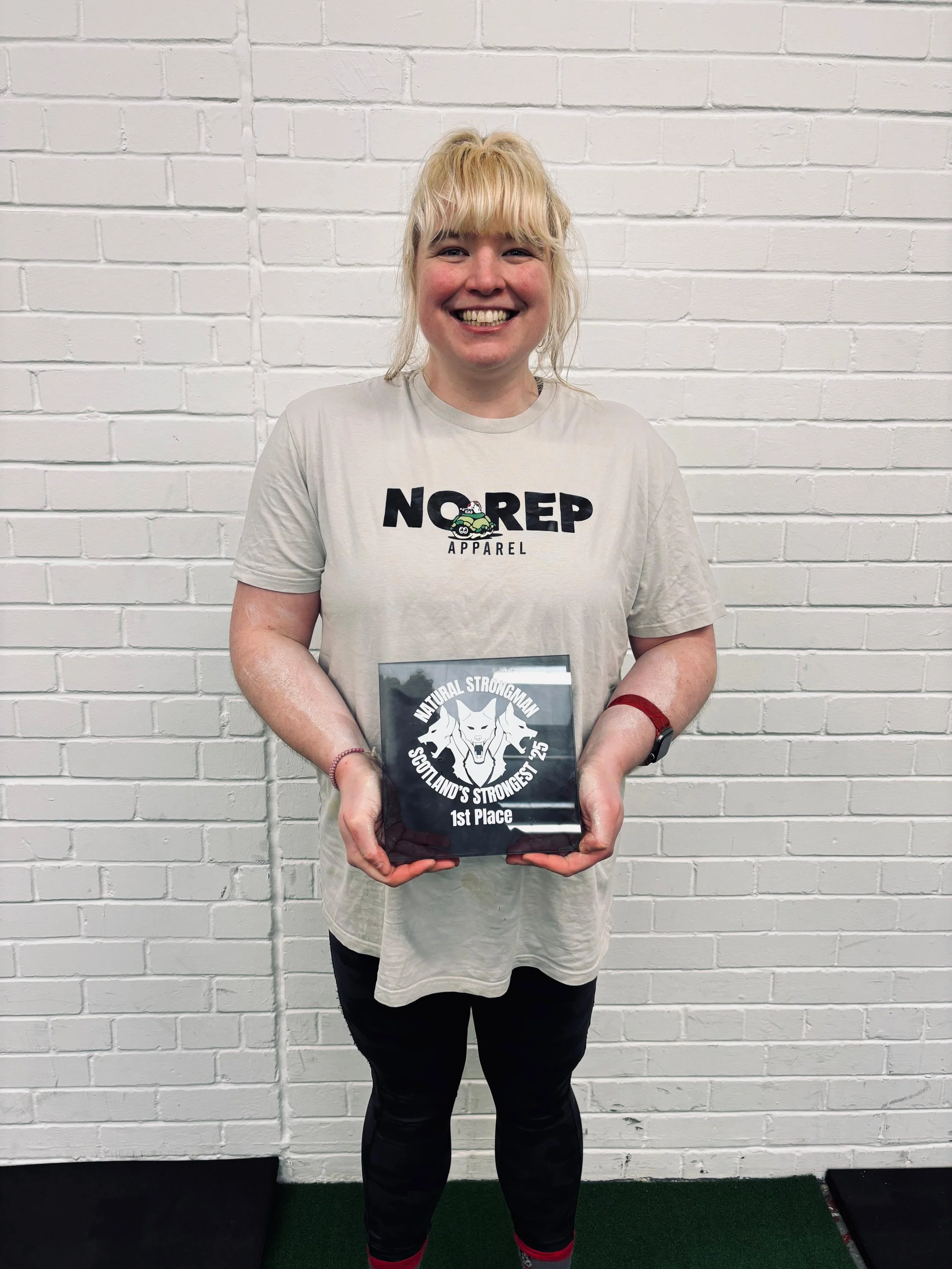 Hope holding her Natural Strongman Scotlands Strongest Woman Trophy