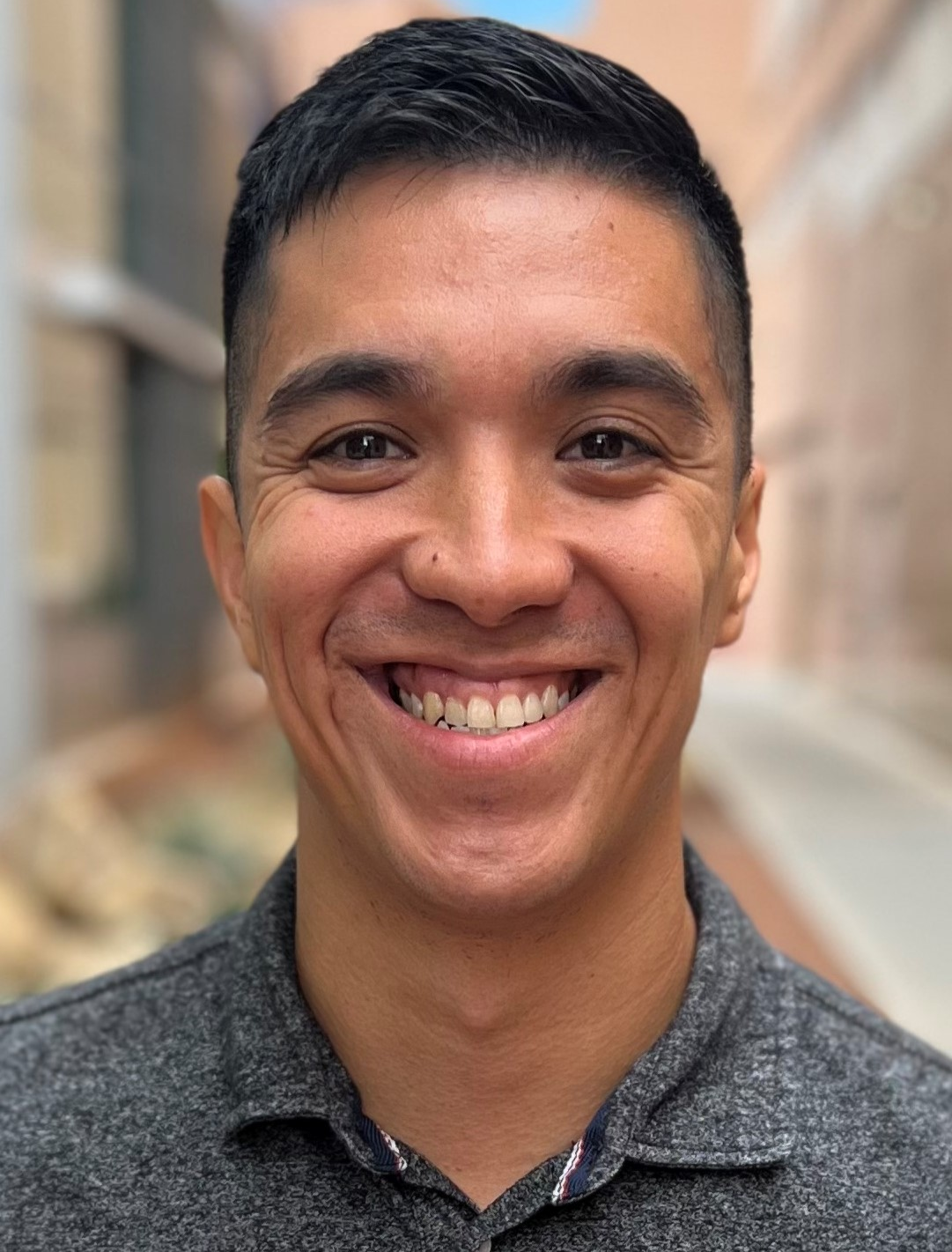 Smiling woman with curly hair, glasses, and hoop earrings, wearing a striped shirt in a cozy indoor setting.