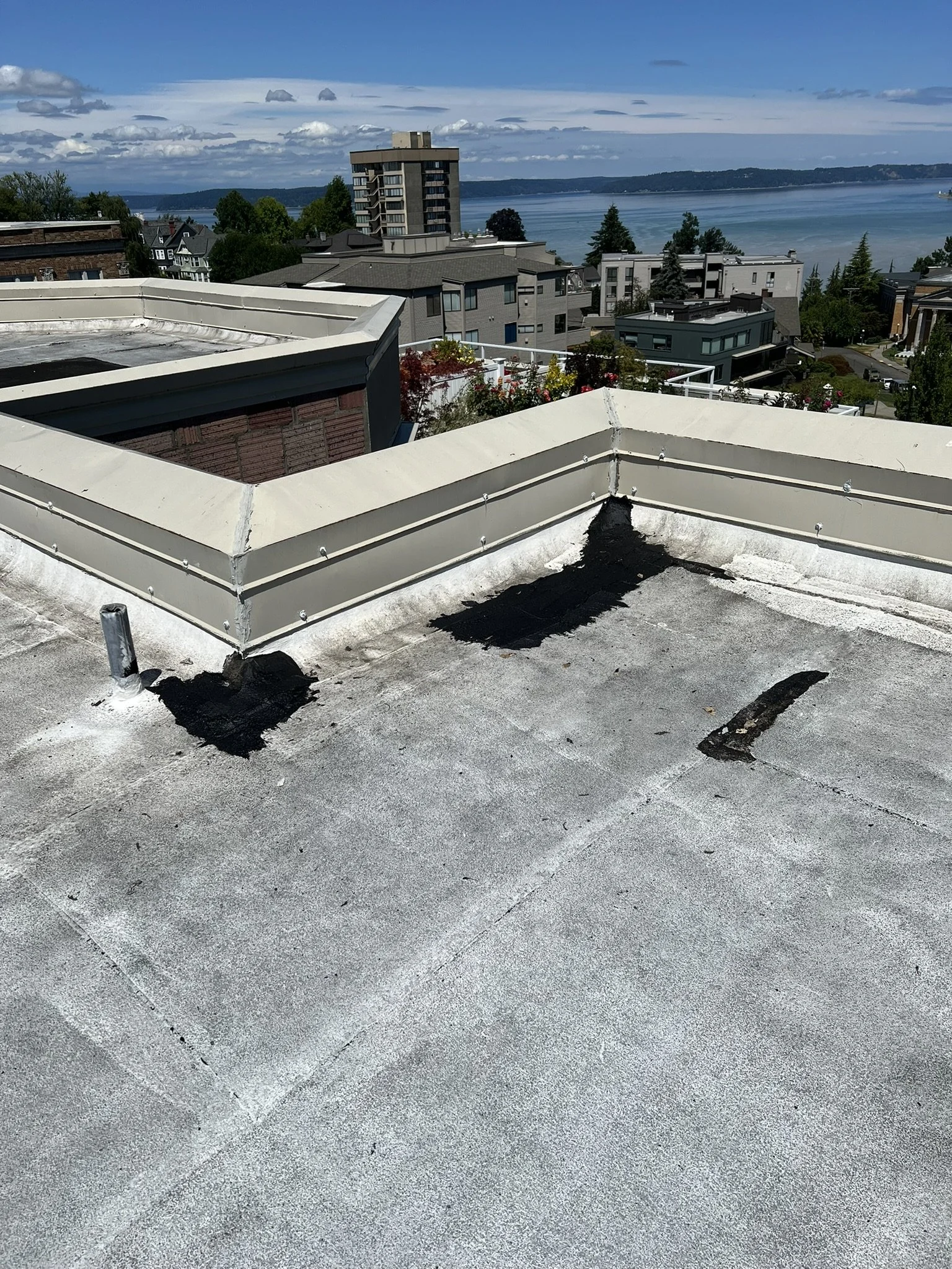 View of rooftops and a body of water in the distance, with a cloudy sky overhead.