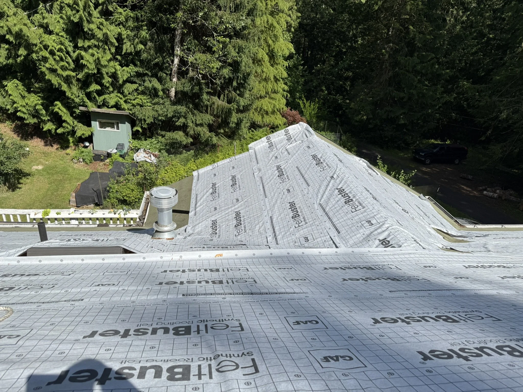 View from the roof of a house under construction or renovation, showing roofing underlayment with the brand name 'FELIBUSTER' and some ventilation pipes.