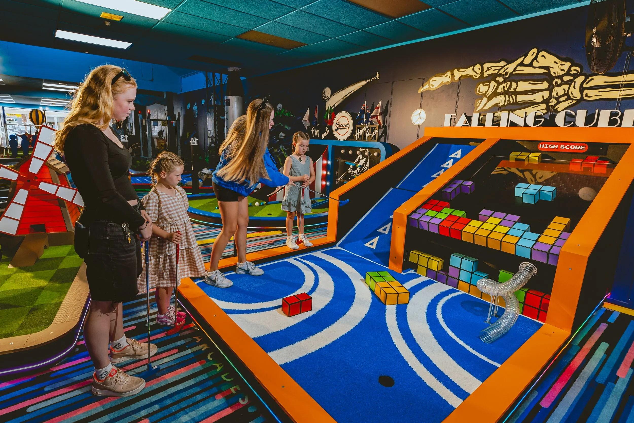 Group of children playing arcade game with colorful blocks at an indoor amusement venue.
