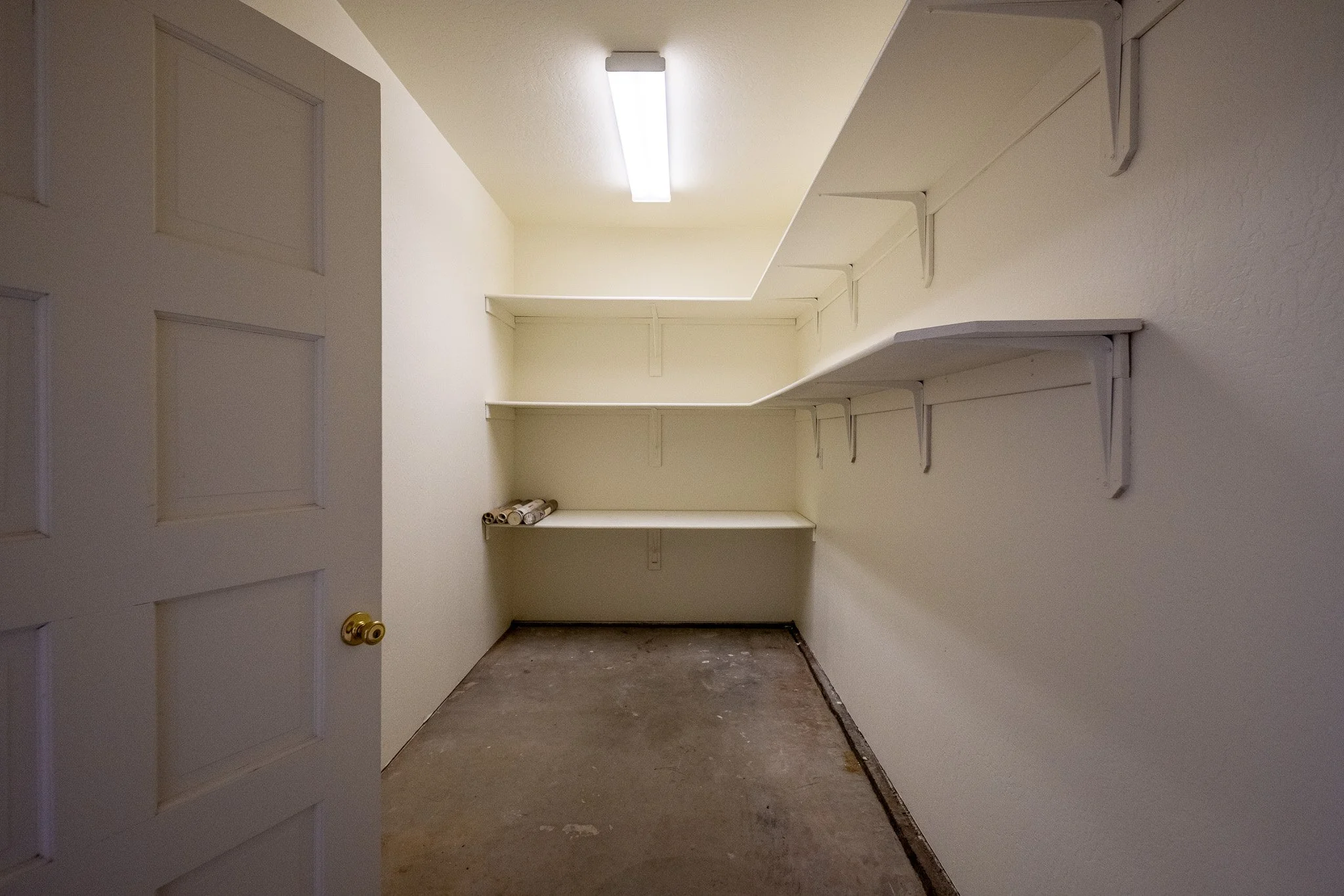 Empty walk-in storage closet with built-in shelves on the right wall and a bare floor.