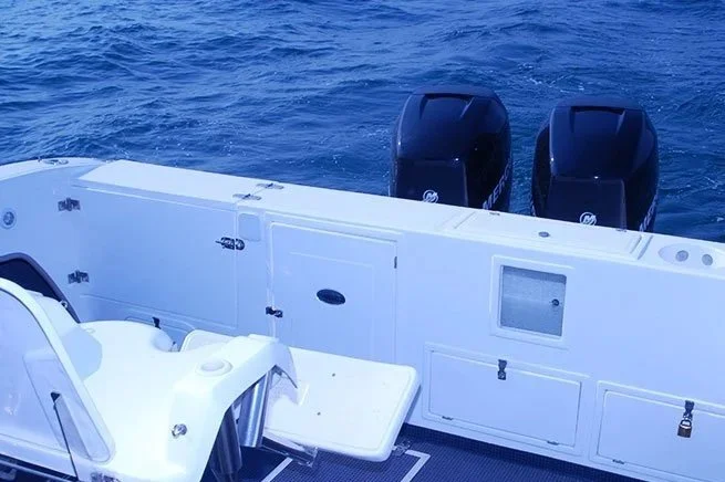 View of a boat's stern with two outboard motors and a seating area on a body of water.