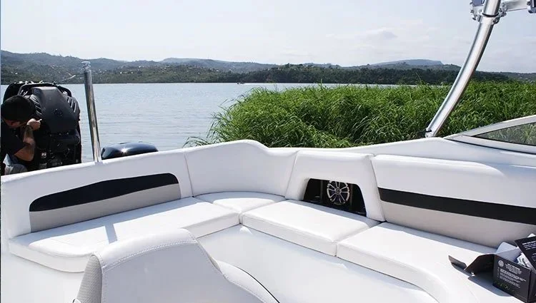Seating area on a white boat with a lake and distant hills in the background.